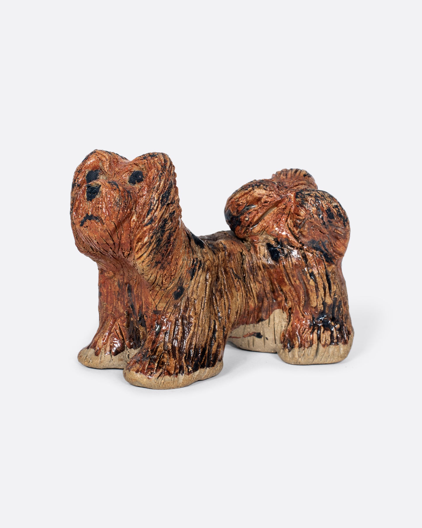 A handmade ceramic dog sculpture. Shown from the side.