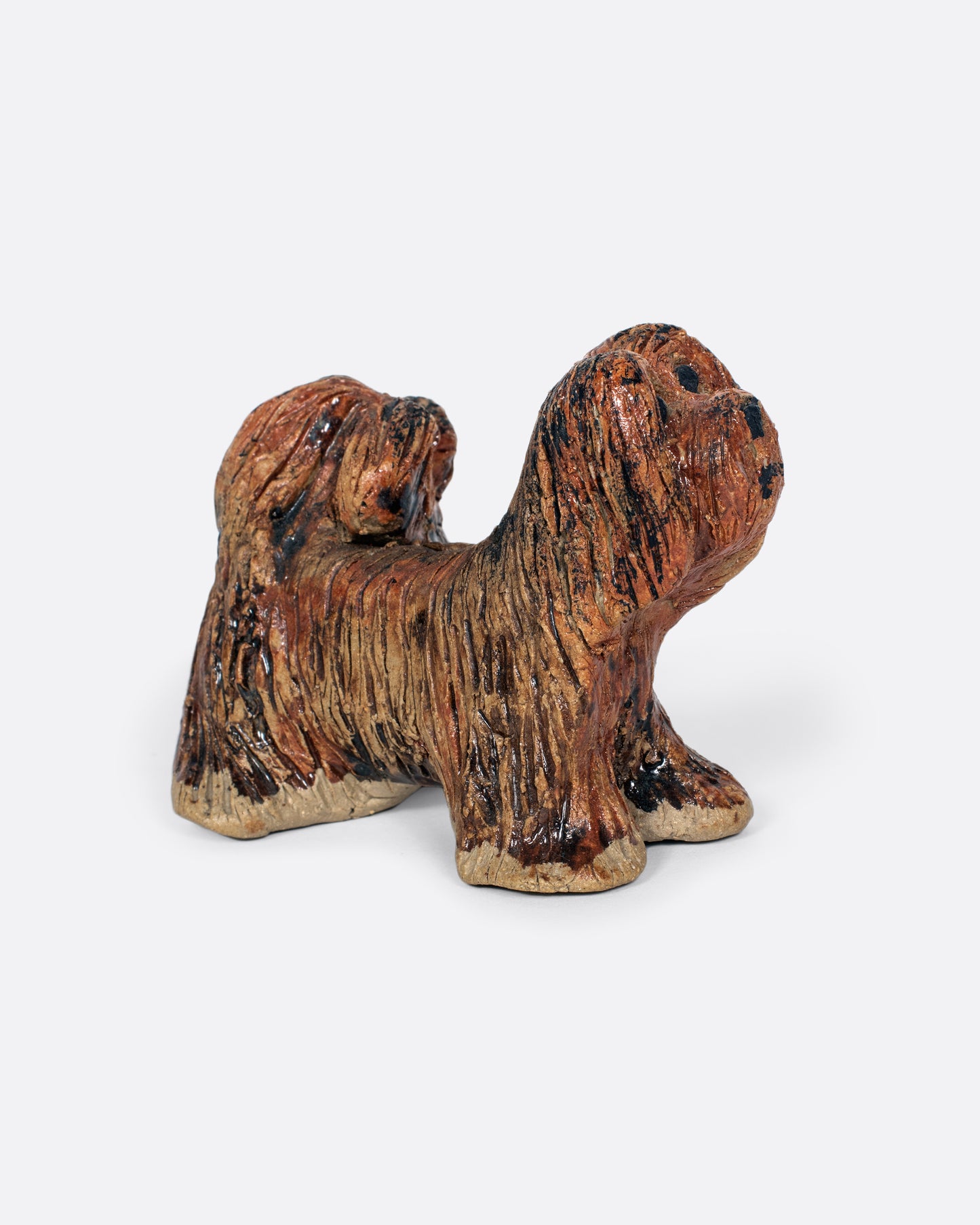 A handmade ceramic dog sculpture. Shown from the side.