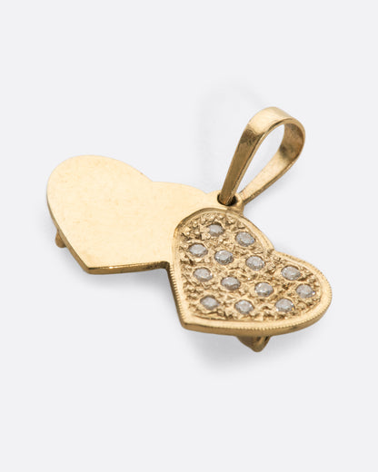 A yellow gold double heart charm with pavé diamonds over a stipple finish on one heart. Shown from the front.