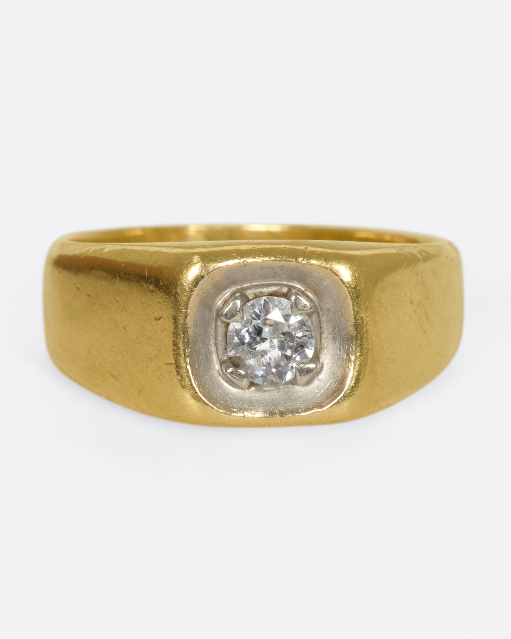 A vintage gold signet ring with a sunken diamond at its center.