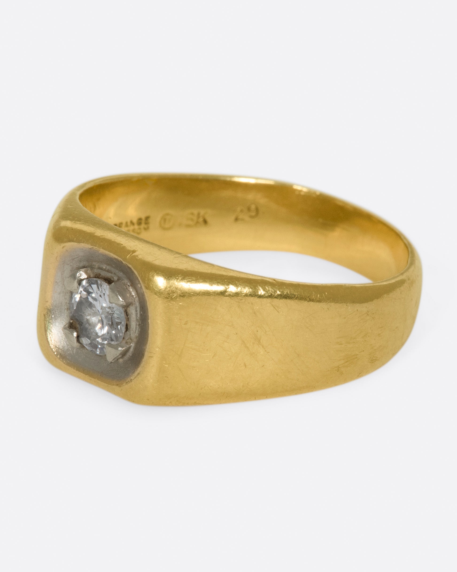 A vintage gold signet ring with a sunken diamond at its center.