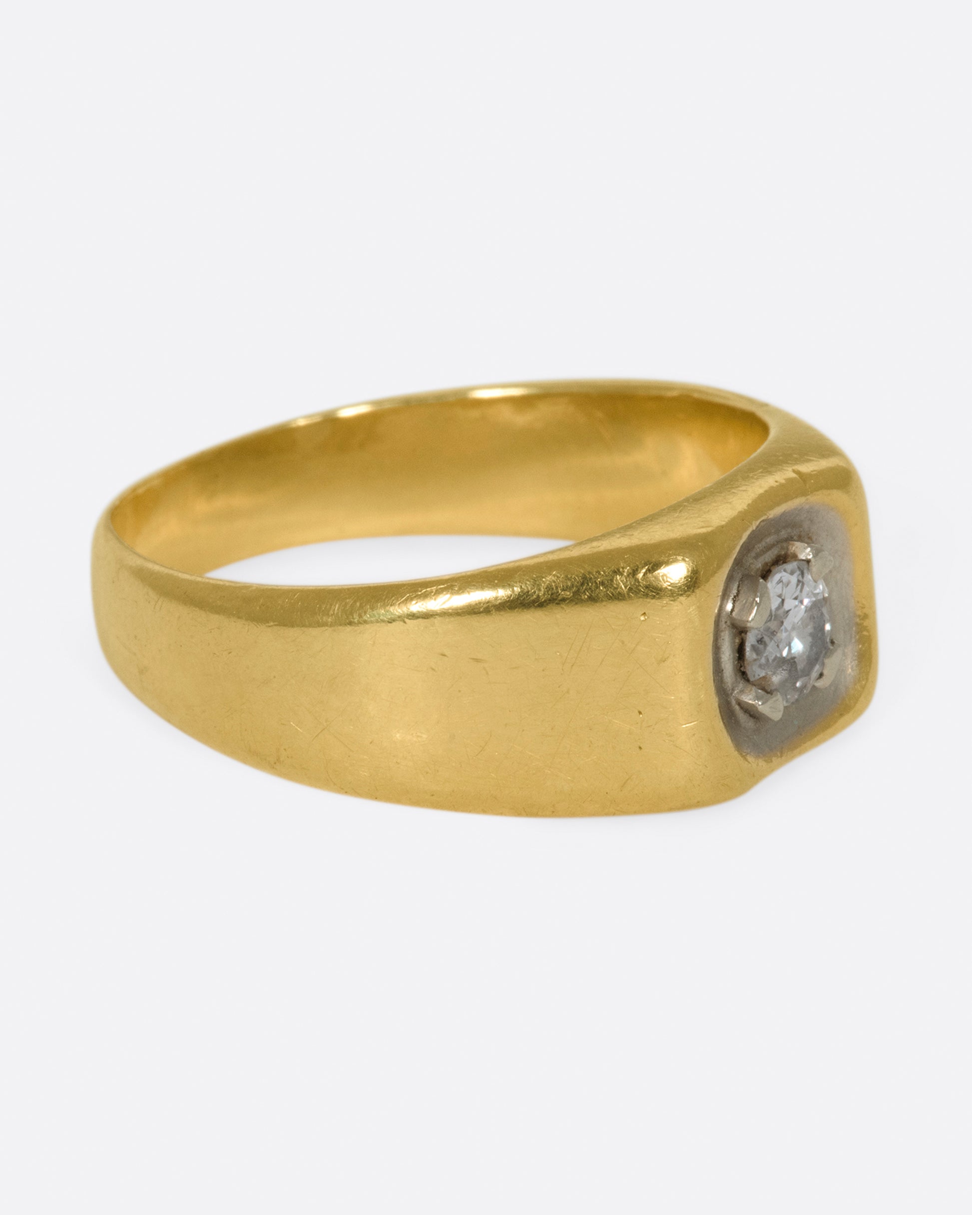 A vintage gold signet ring with a sunken diamond at its center.