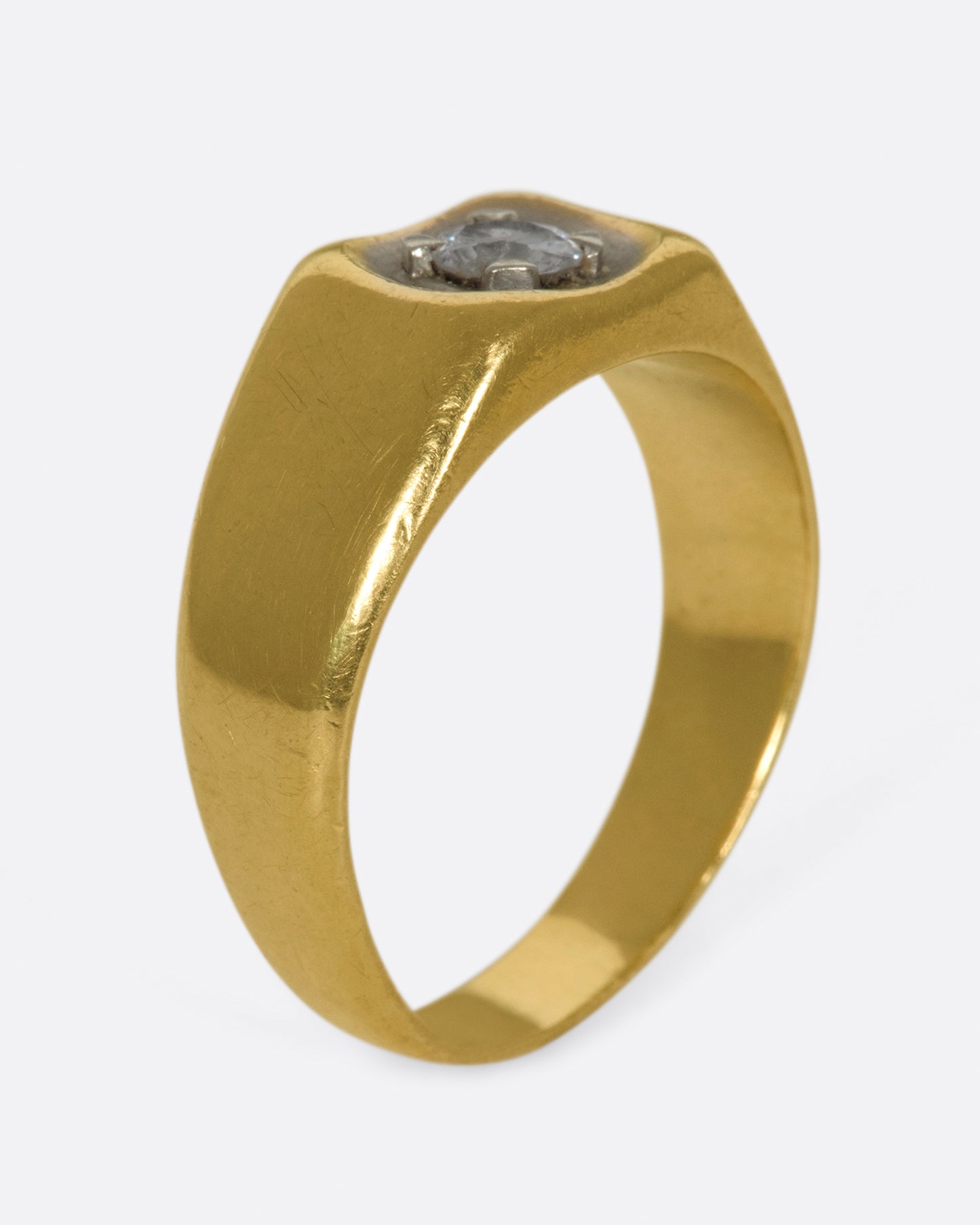 A vintage gold signet ring with a sunken diamond at its center.