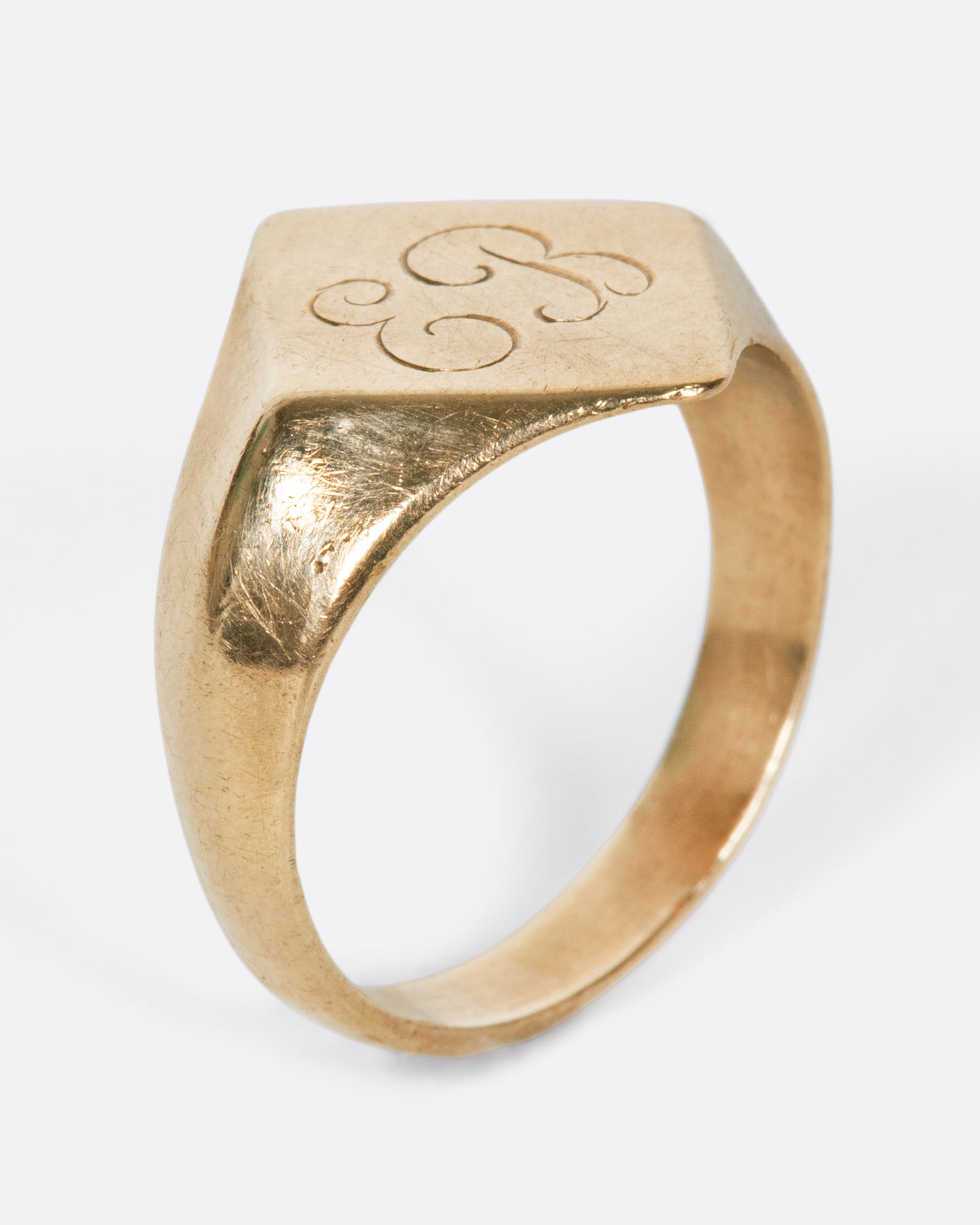 A vintage yellow gold signet ring with a diamond shaped face and the initials EB engraved on the front.