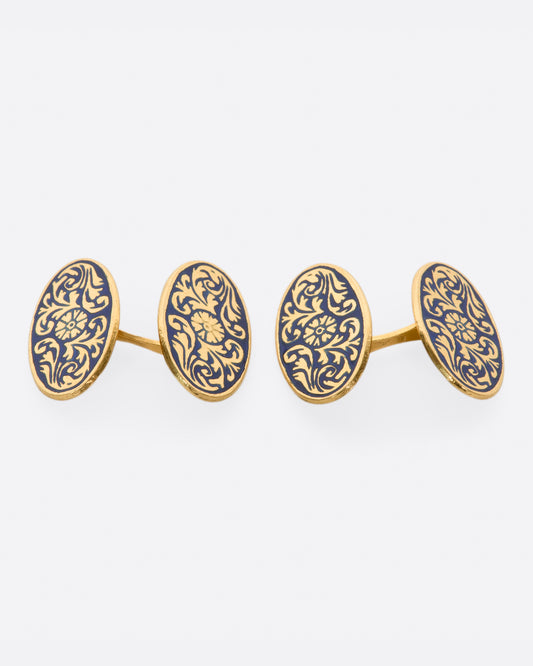 A pair of solid gold vintage cufflinks with intricate flourishes and contrasting dark blue enamel.