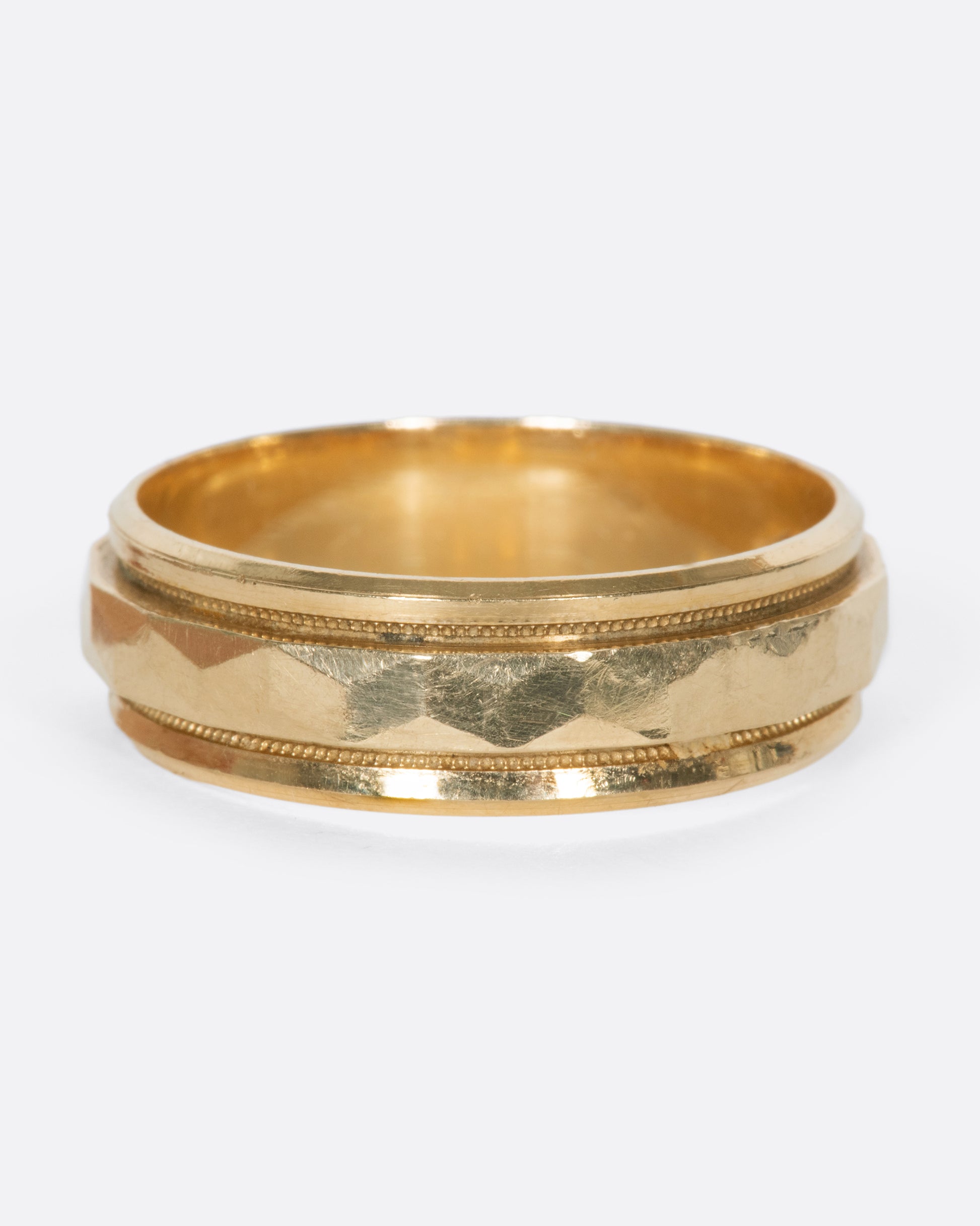 A vintage yellow gold band with geometric faceting down the center.