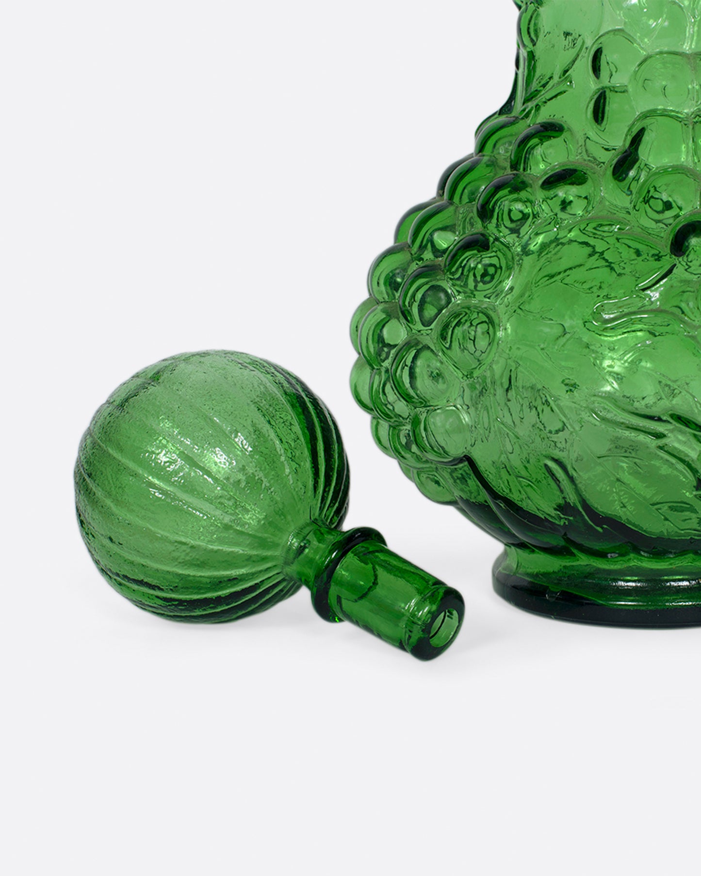 A tall, bottle green glass decanter with a textured stopper.