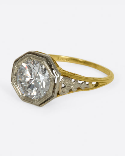 Vintage gold diamond ring, side view with the diamond facing left and scrolling filigree on the shoulders