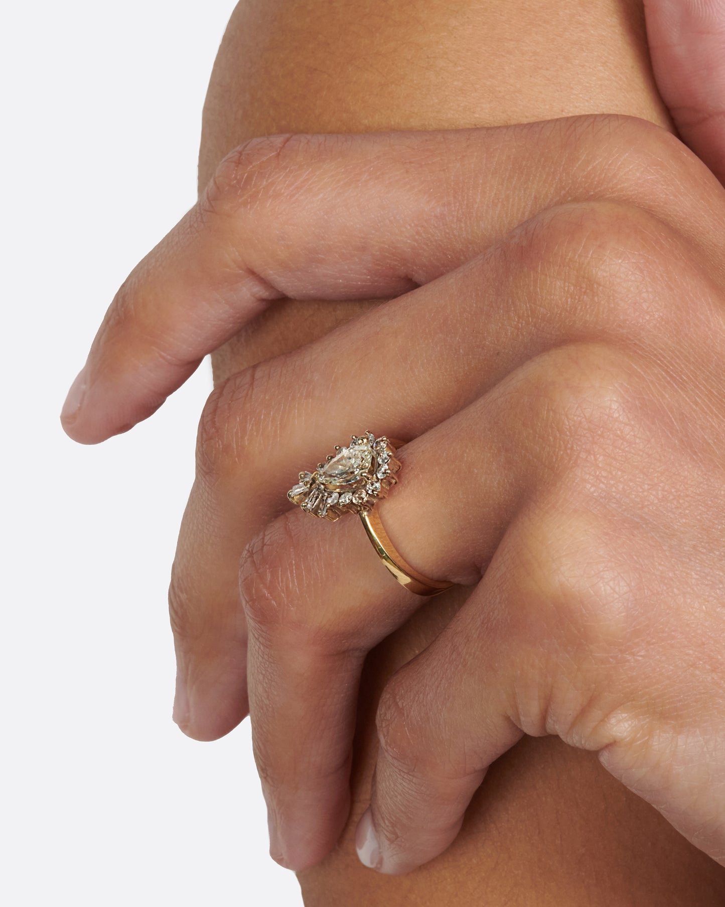 A tapered ring with a pale yellow, pear shaped diamond at its center with a round and baguette diamond halo.