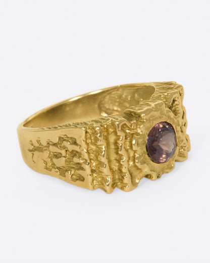 A right side view of a yellow gold ring with ribbon texture and round pink spinel.
