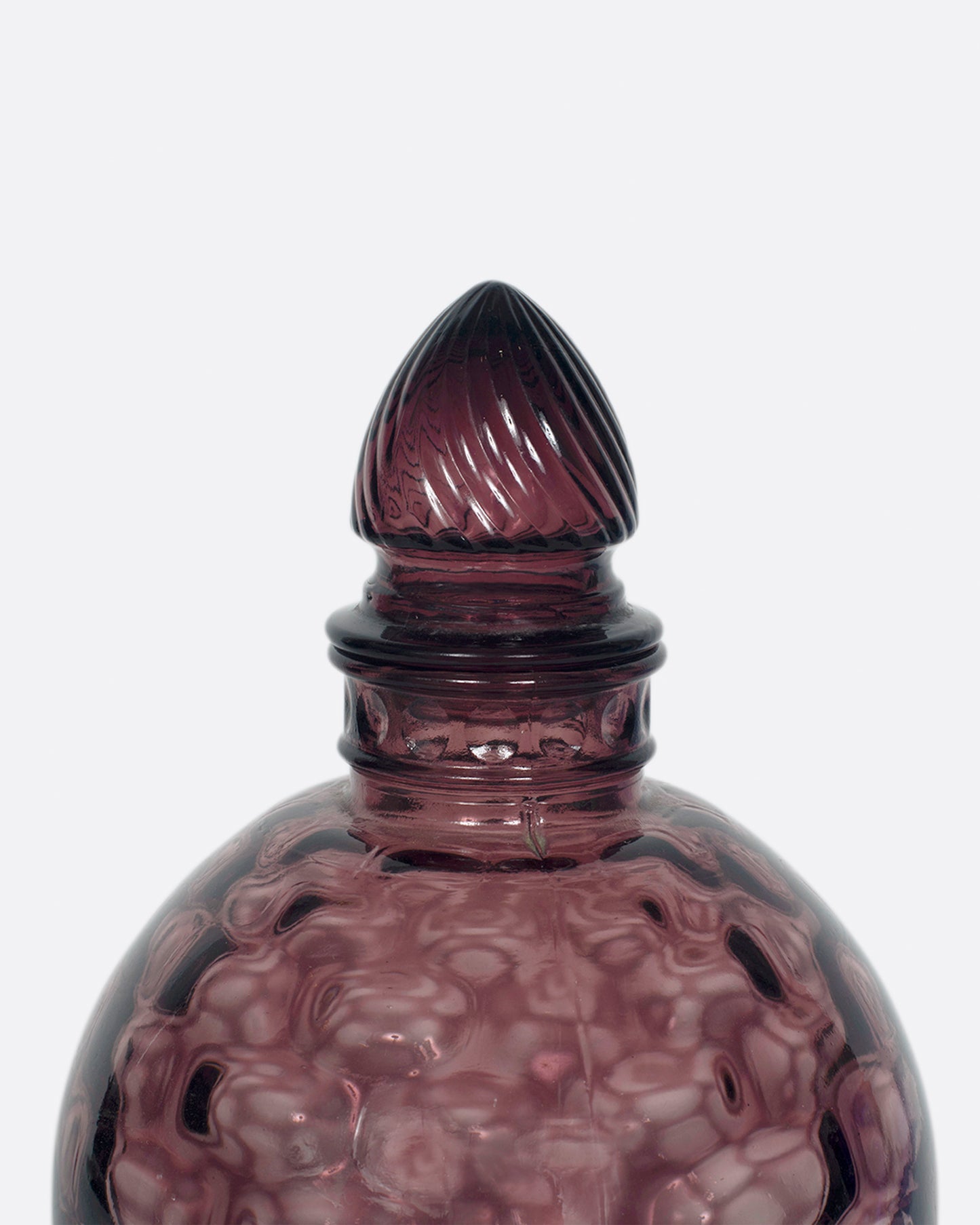 A dark plum, bubble glass bottle with an acorn-shaped stopper.