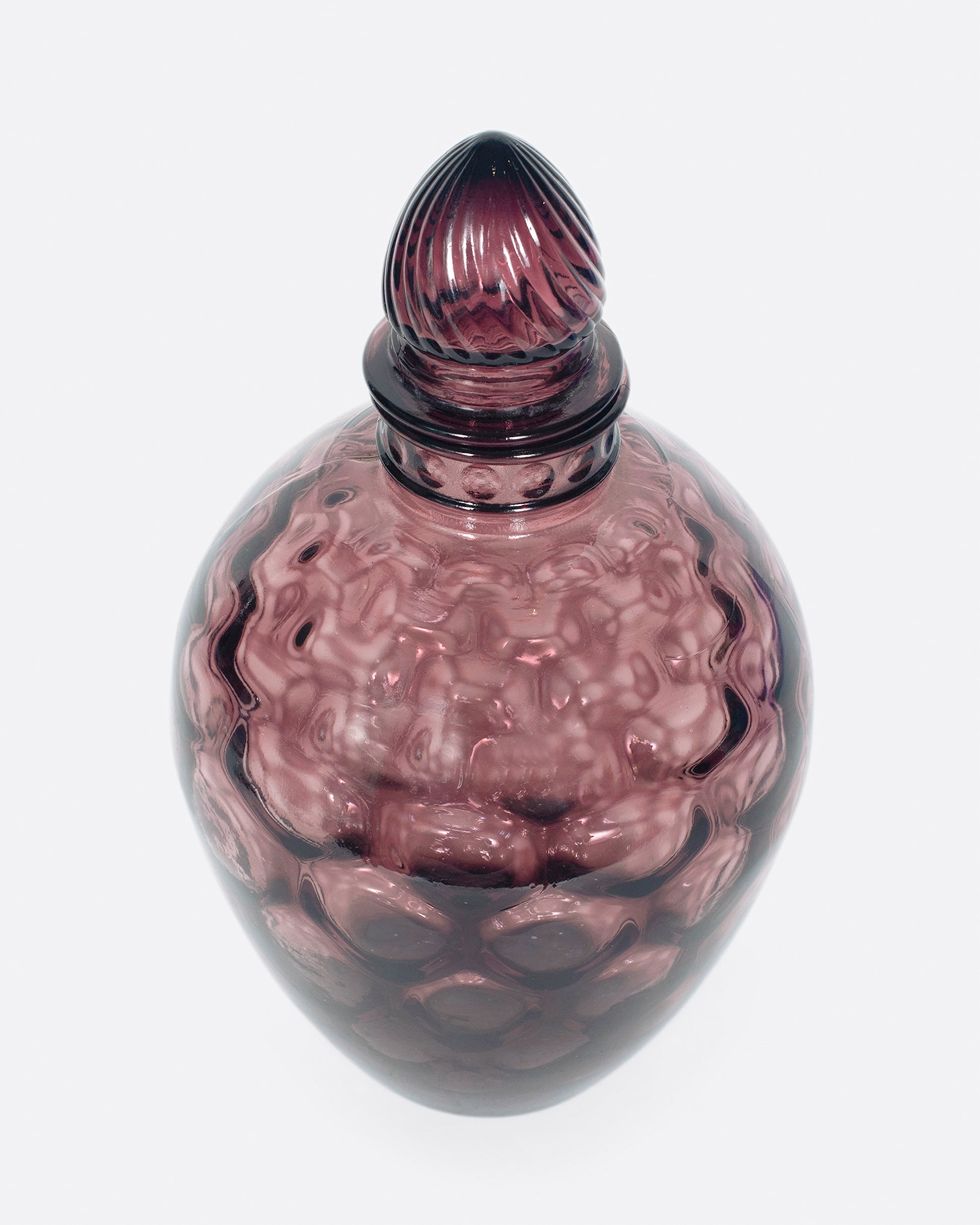 A dark plum, bubble glass bottle with an acorn-shaped stopper.