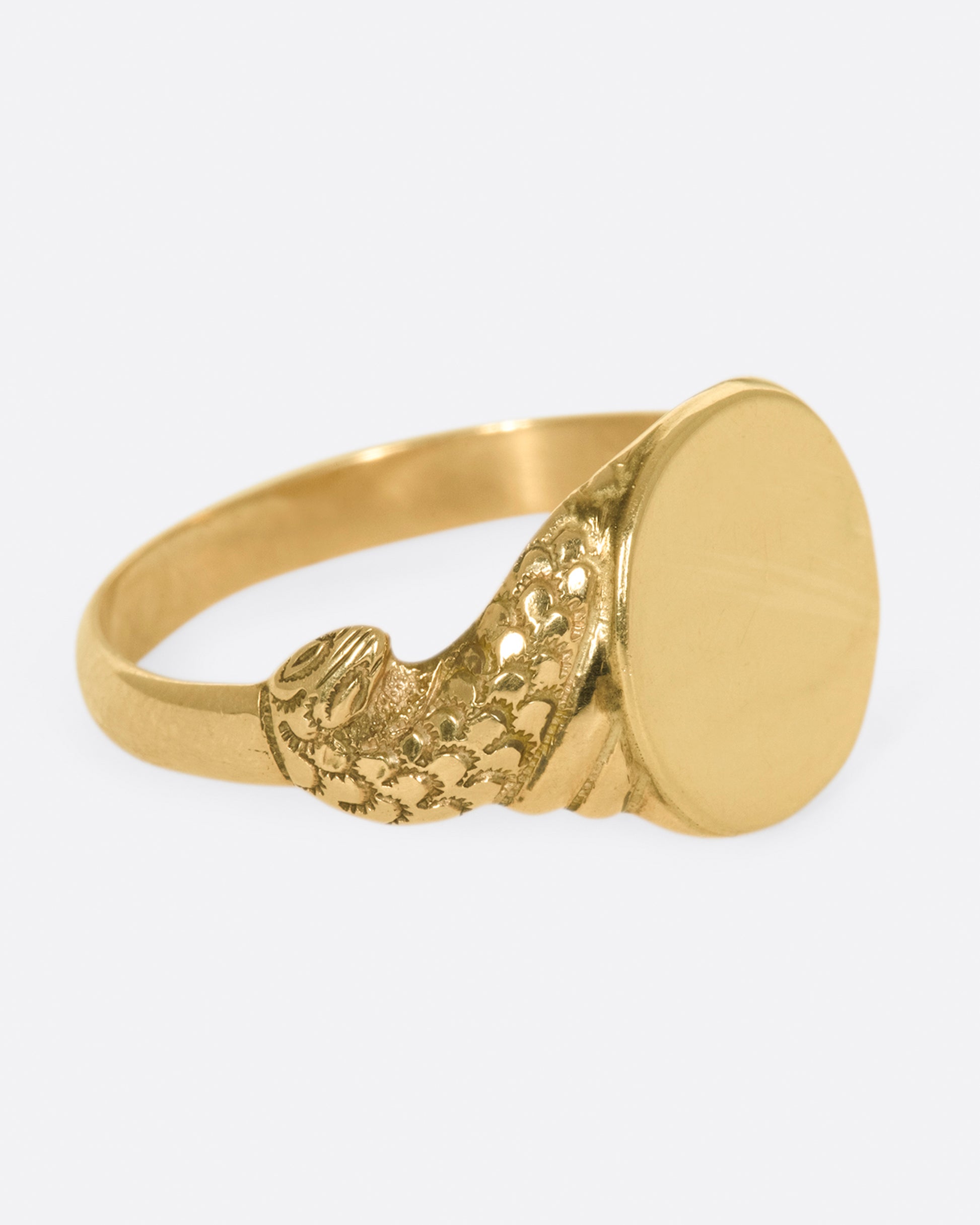 A classic, blank signet ring with carved snakes swirling around the band.