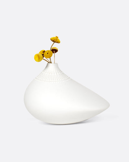 Vintage white porcelain bud vase, a low teardrop shape with a small opening and fine dotted texture, holding small yellow flowers