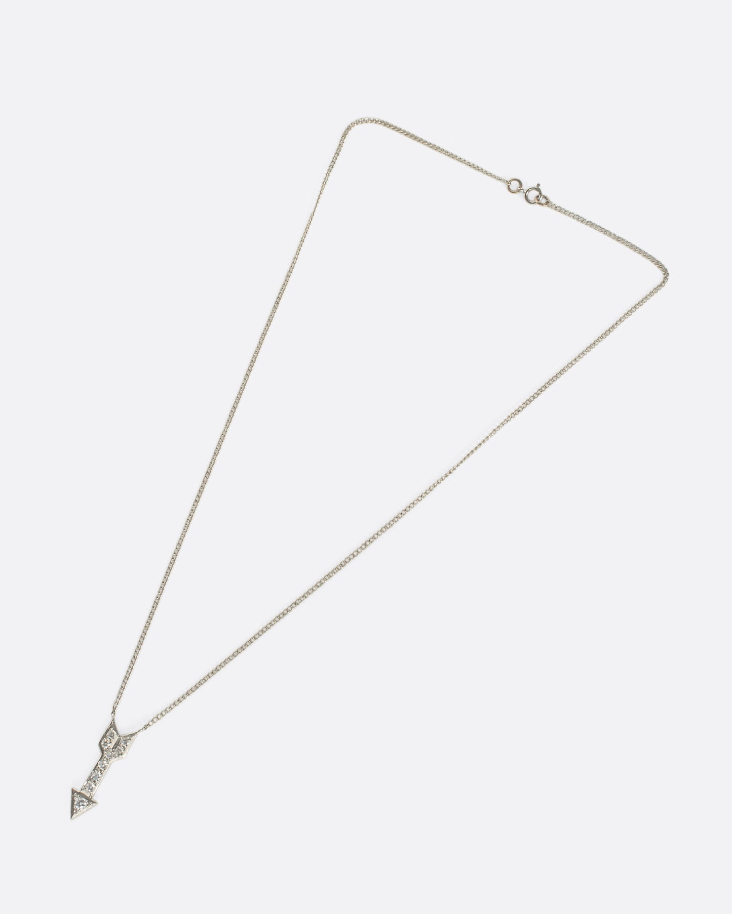 A narrow curb chain is fixed directly to either side of this diamond-lined pendant.