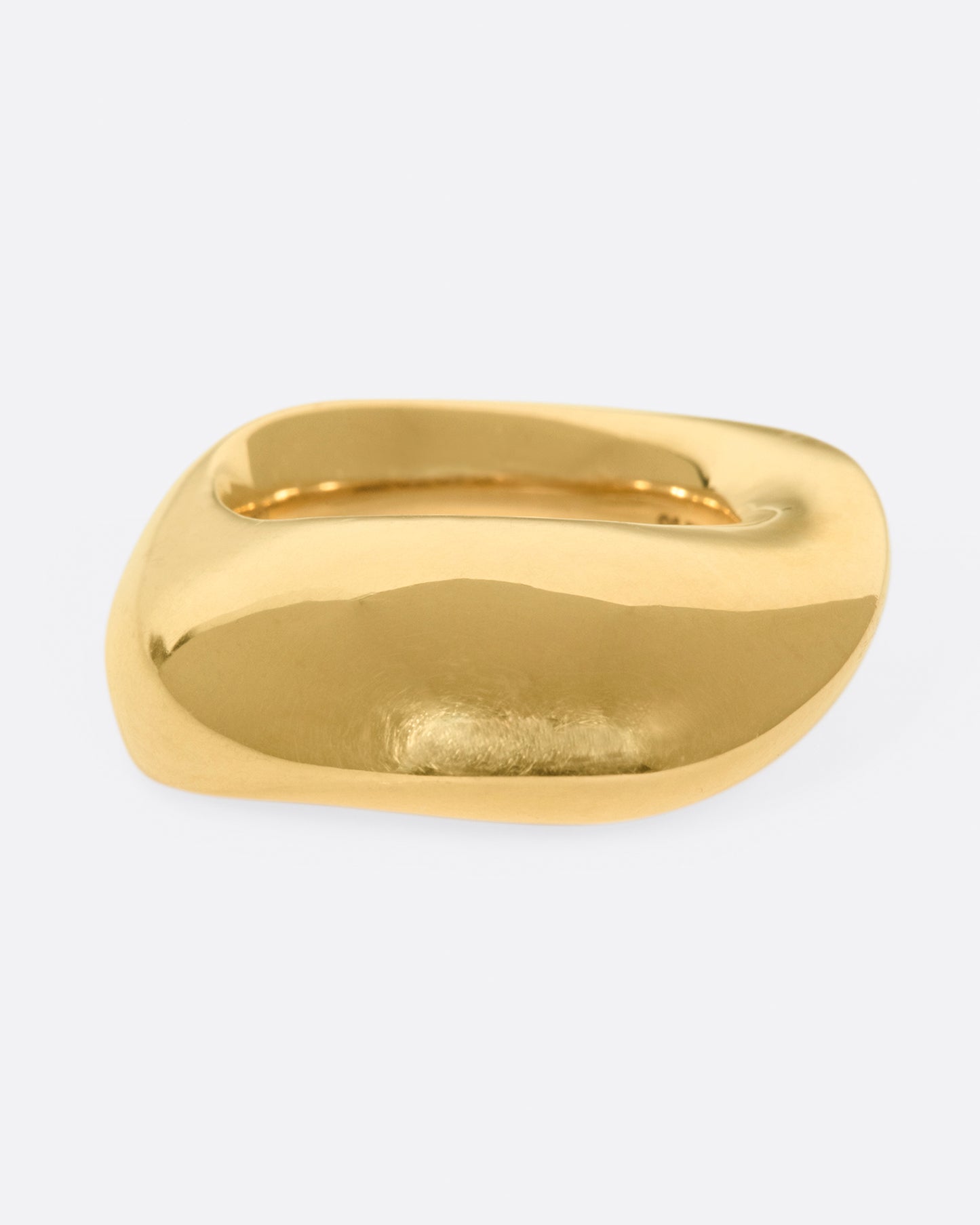 An abstract shaped gold ring with a yin yang symbol cutout on the inside of the band.