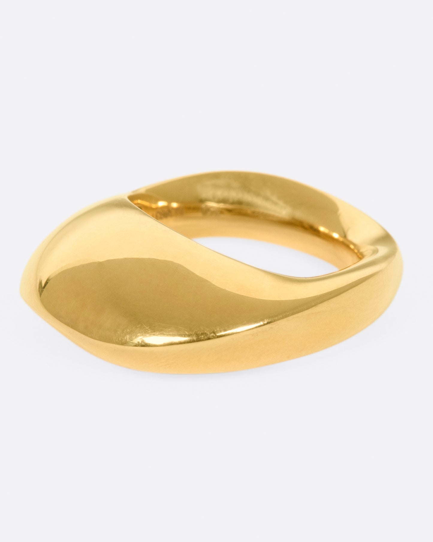 An abstract shaped gold ring with a yin yang symbol cutout on the inside of the band.