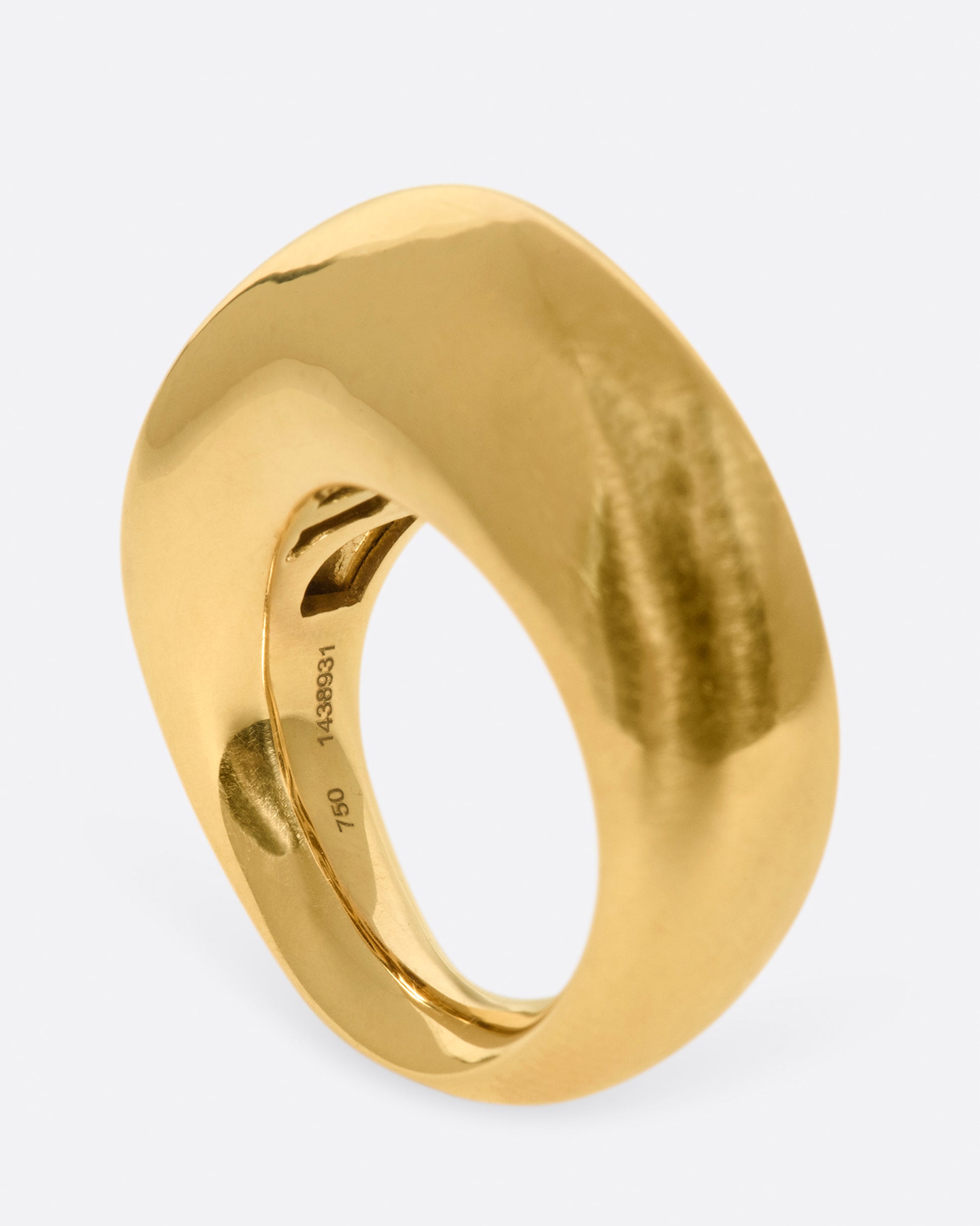 An abstract shaped gold ring with a yin yang symbol cutout on the inside of the band.