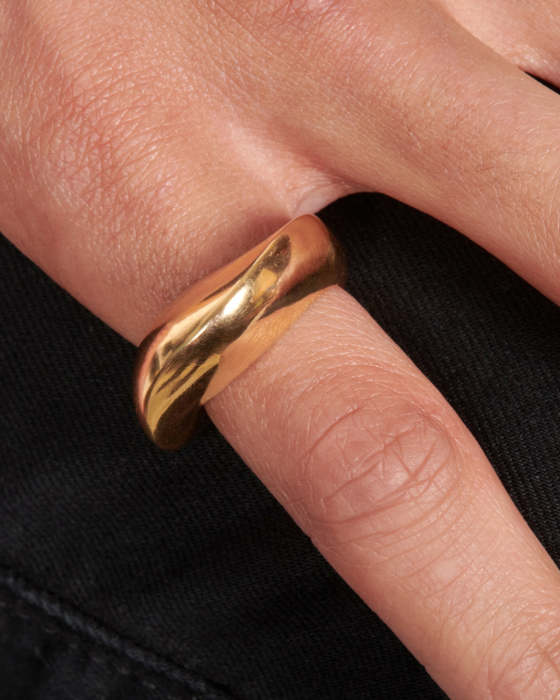 An abstract shaped gold ring with a yin yang symbol cutout on the inside of the band.