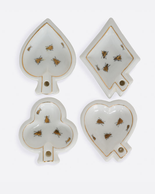 Four white ceramic dishes shaped like playing card suits with  gold trim and bug designs. Shown from the top.
