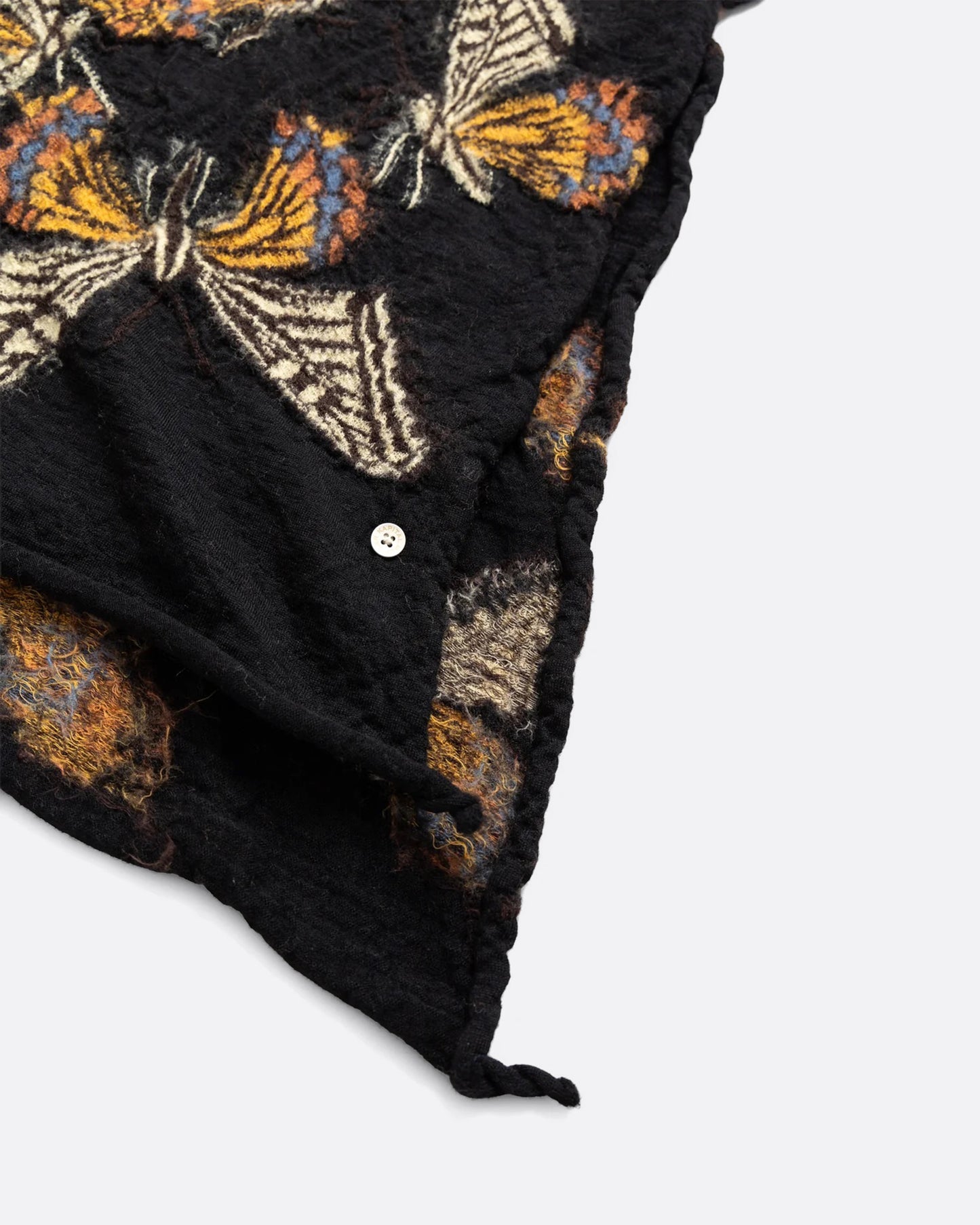 A close up of a black compressed wool scarf with butterflies all over it.