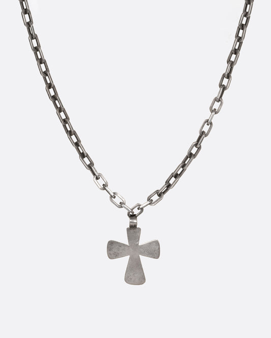 A heavy cable chain necklace with a large cross pendant. Shown up close from the front.