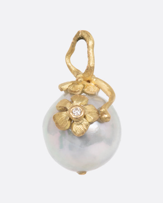 Pearl pendant with a yellow gold bale featuring two small flowers, one with a diamond center. View from the front.