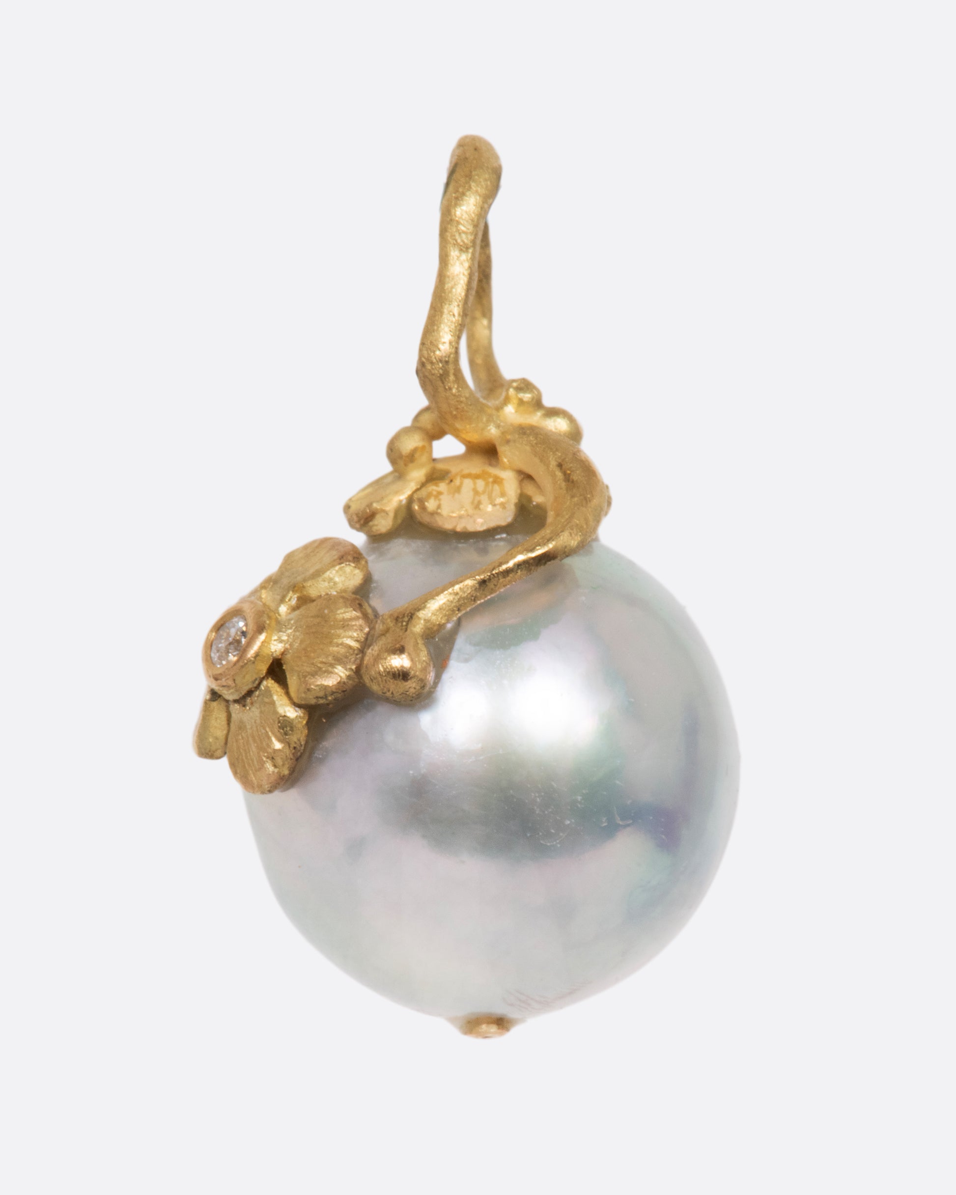 Pearl pendant with a yellow gold bale featuring two small flowers, one with a diamond center. View from the side.