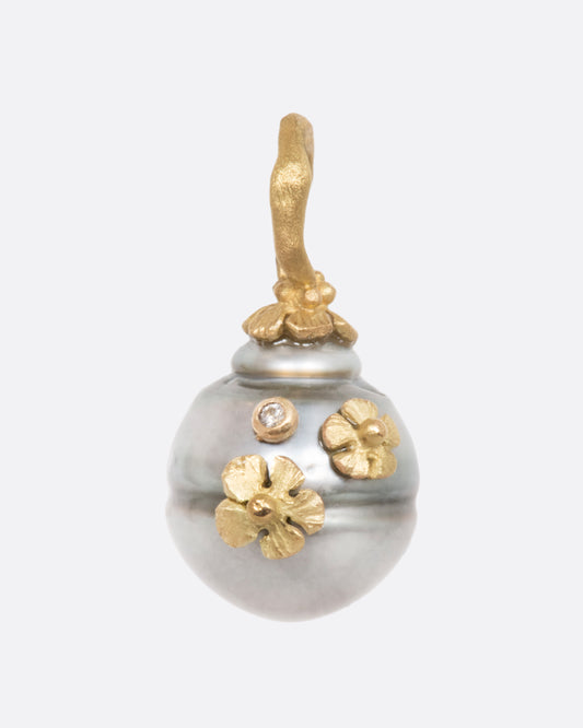 A pearl pendant with a yellow gold bale, adorned with tiny flowers and a diamond. View from the front.