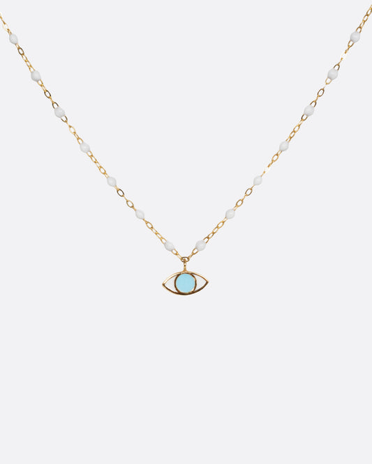 A yellow gold cable chain necklace with droplets of white resin and an eye charm. The iris of the eye charm is turquoise blue enamel and the sclera is white. Shown from the front.