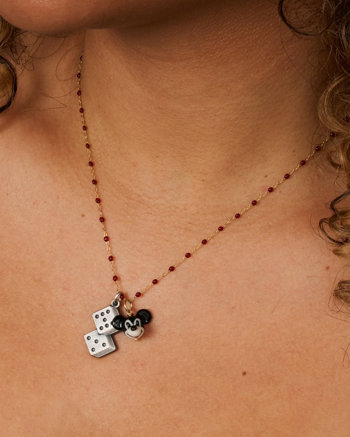 A three dimensional black and white era mickey mouse charm with a yellow gold bail. Charm shown on a resin beaded necklace paired with a dice charm.