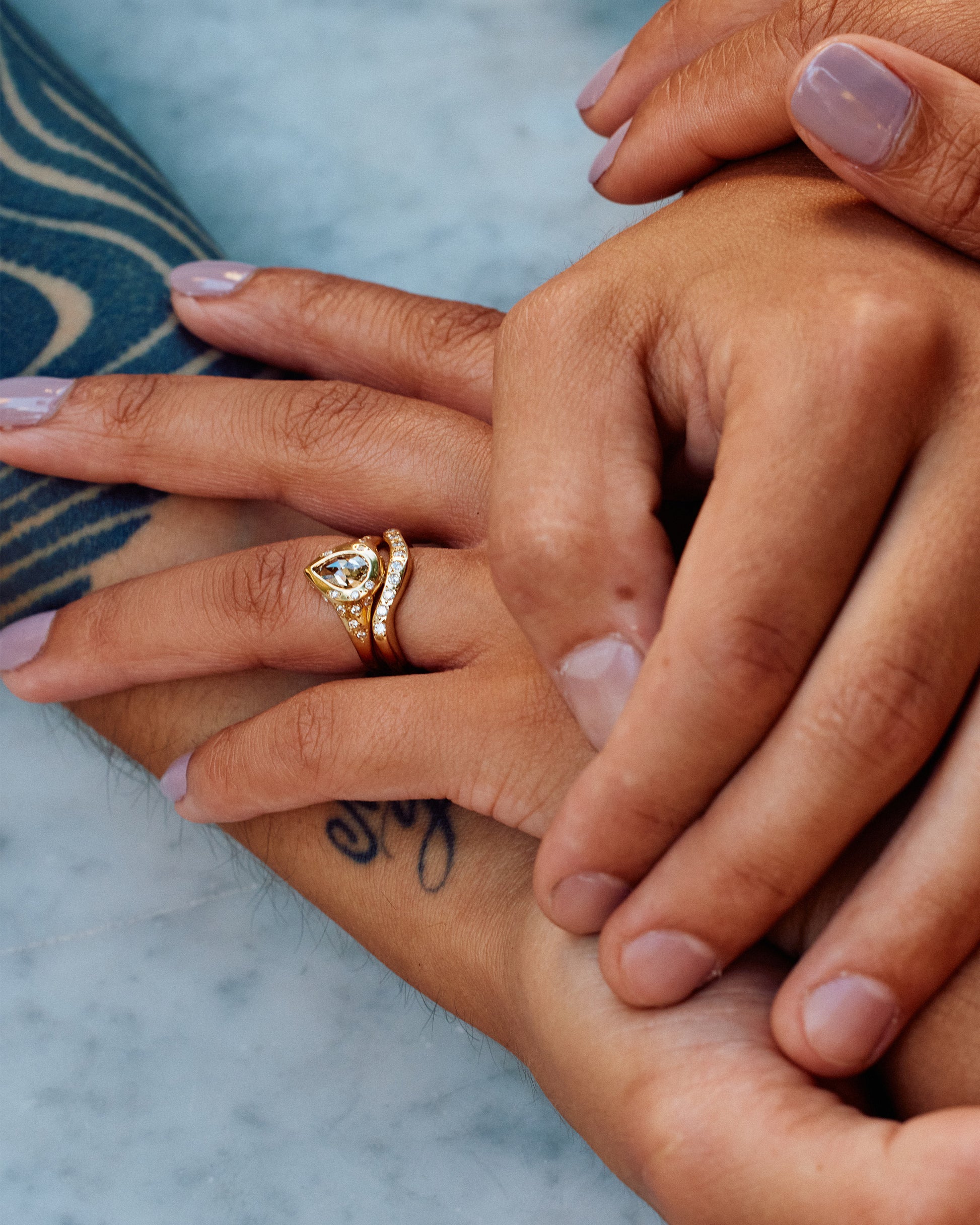 A rose cut, pear shaped, rustic diamond is set in a ring covered in round white diamond stars.