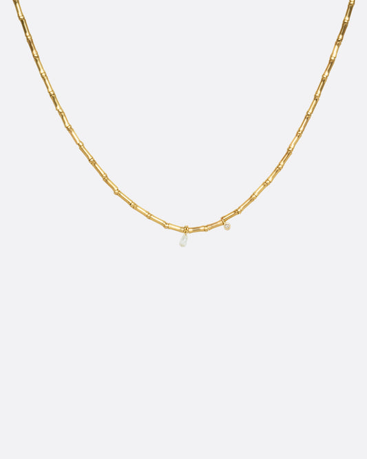 A yellow gold tube beaded necklace with two diamonds. Shown from the front.