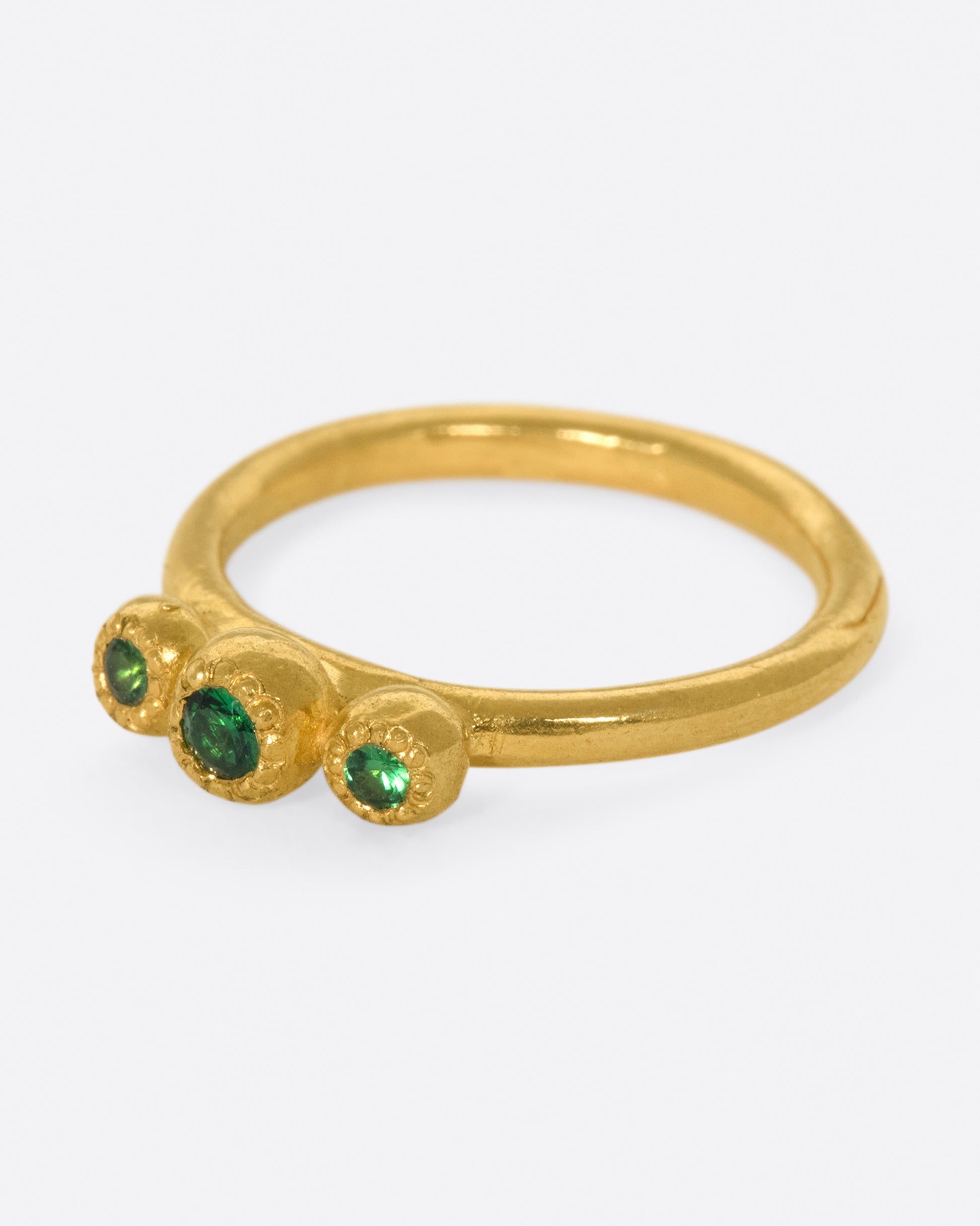 A hand sculpted three stone ring with vivid green tsavorite garnets.