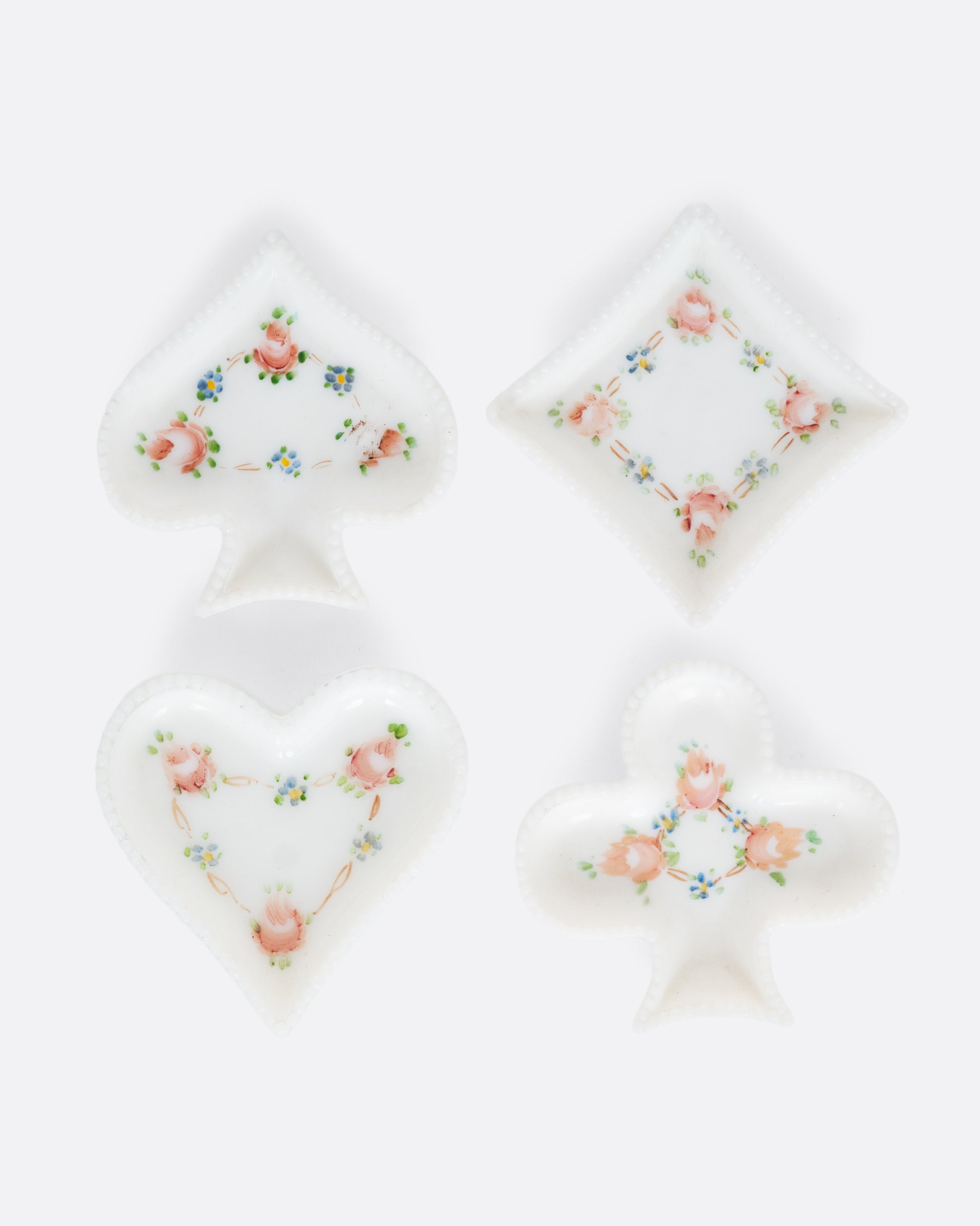 Four white ceramic dishes shaped like playing card suits with  floral designs. Shown from the top.