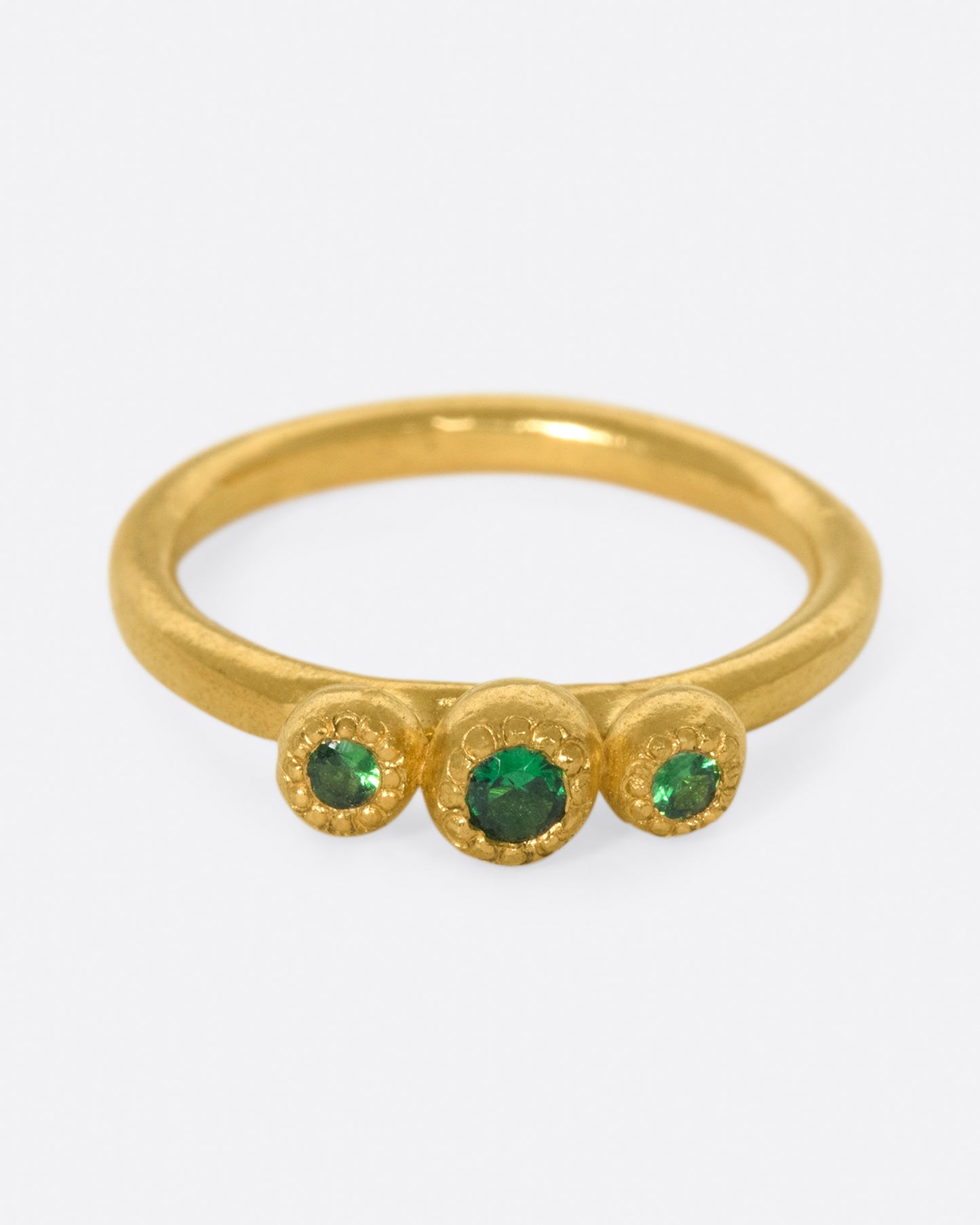 A hand sculpted three stone ring with vivid green tsavorite garnets.