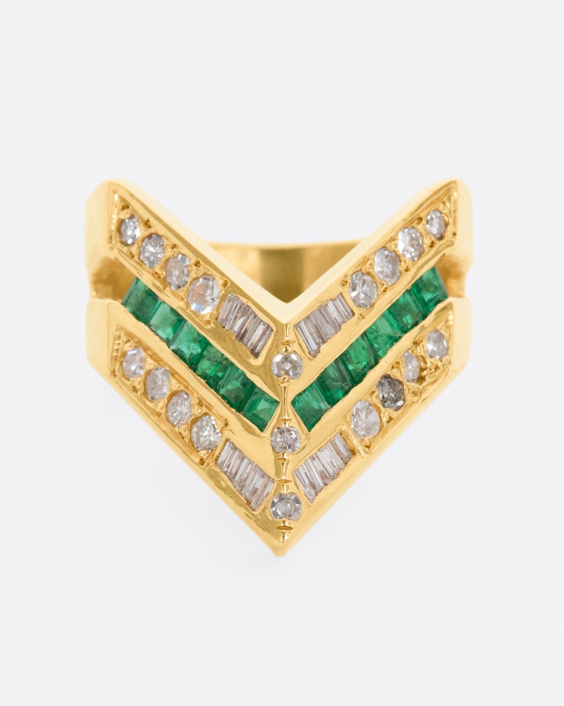 A yellow gold chevron shaped ring with alternating rows of diamonds and emeralds. View from the front.