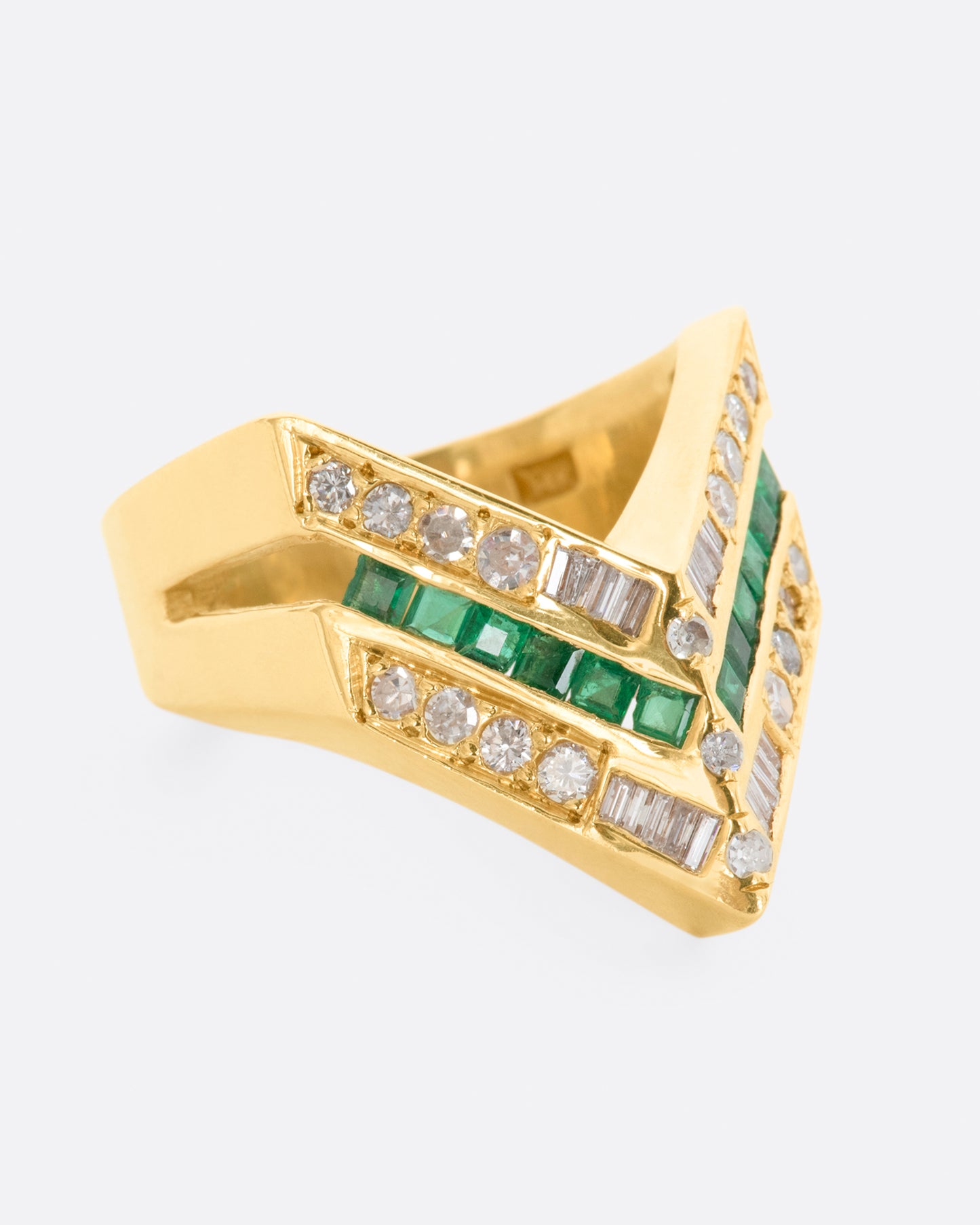 A yellow gold chevron shaped ring with alternating rows of diamonds and emeralds. View from the right side.