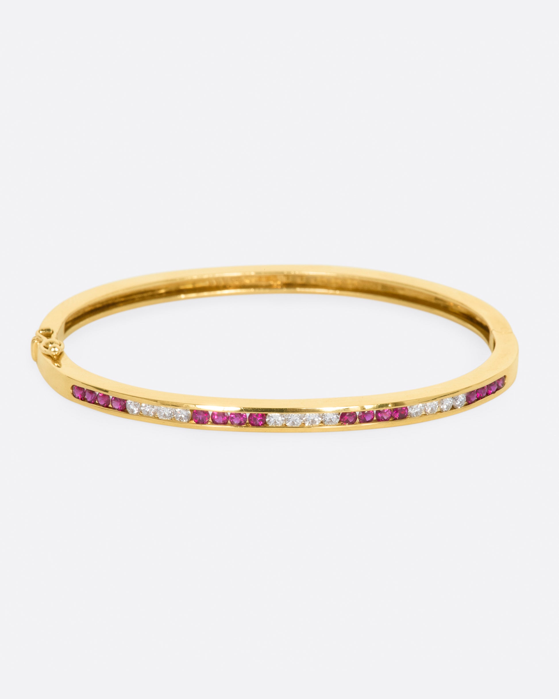 Yellow gold bracelet with alternating sections of channel set rubies and diamonds. View from the front.