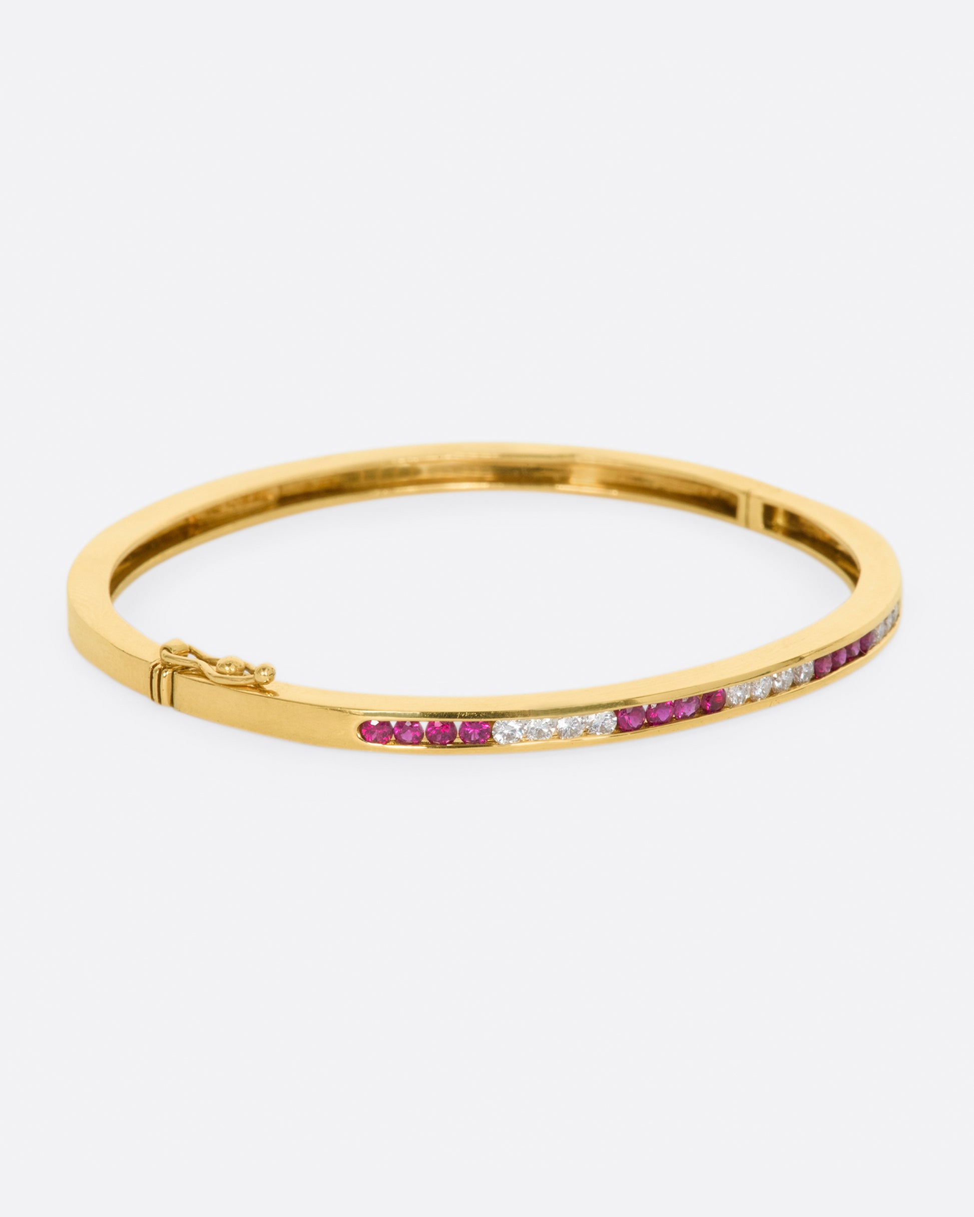 Yellow gold bracelet with alternating sections of channel set rubies and diamonds. View from the right side.