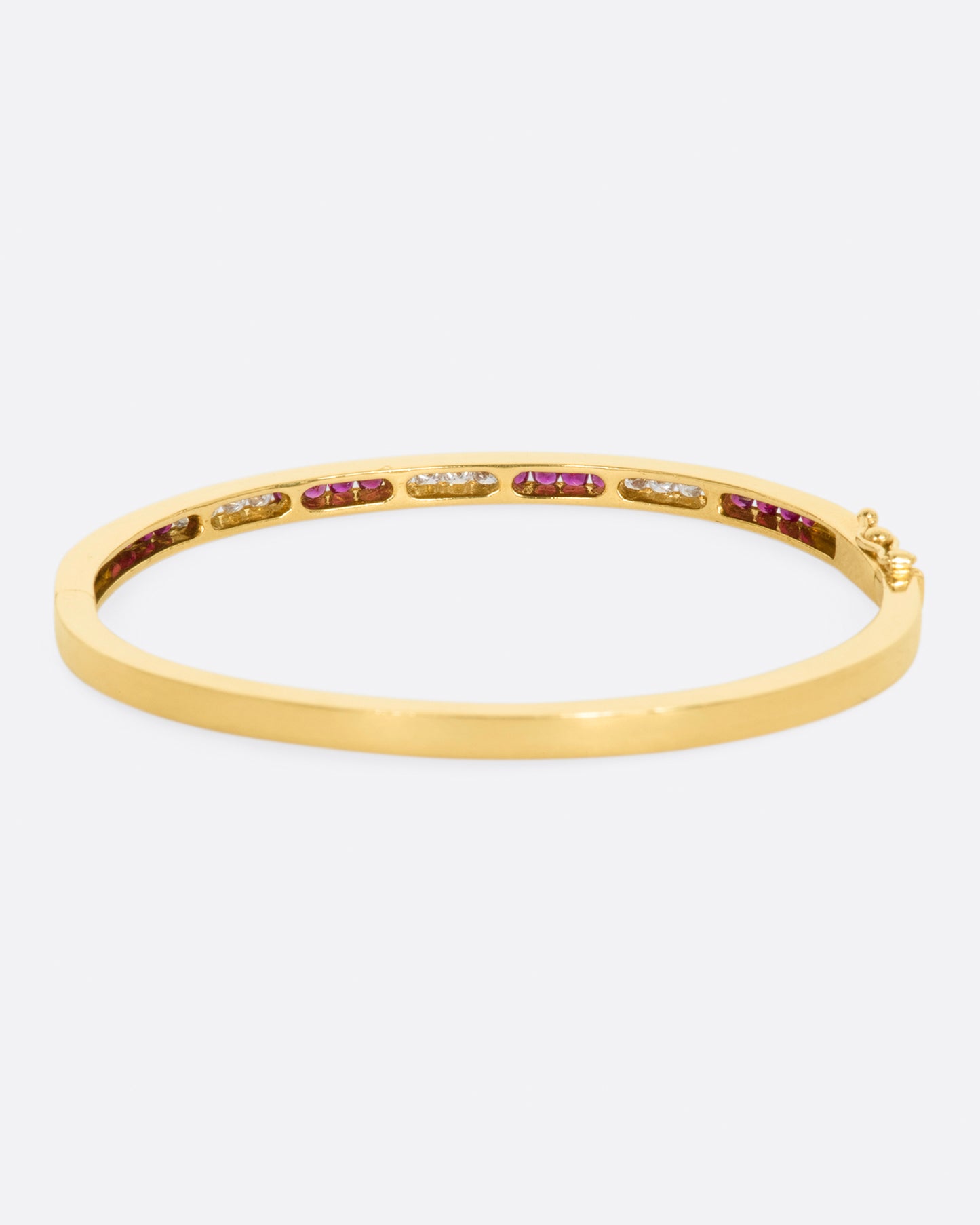 Yellow gold bracelet with alternating sections of channel set rubies and diamonds. View from the back.