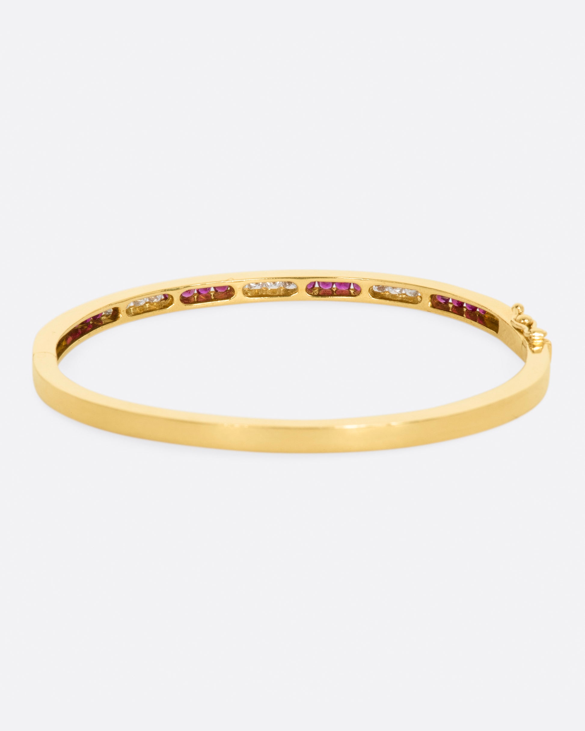 Yellow gold bracelet with alternating sections of channel set rubies and diamonds. View from the back.