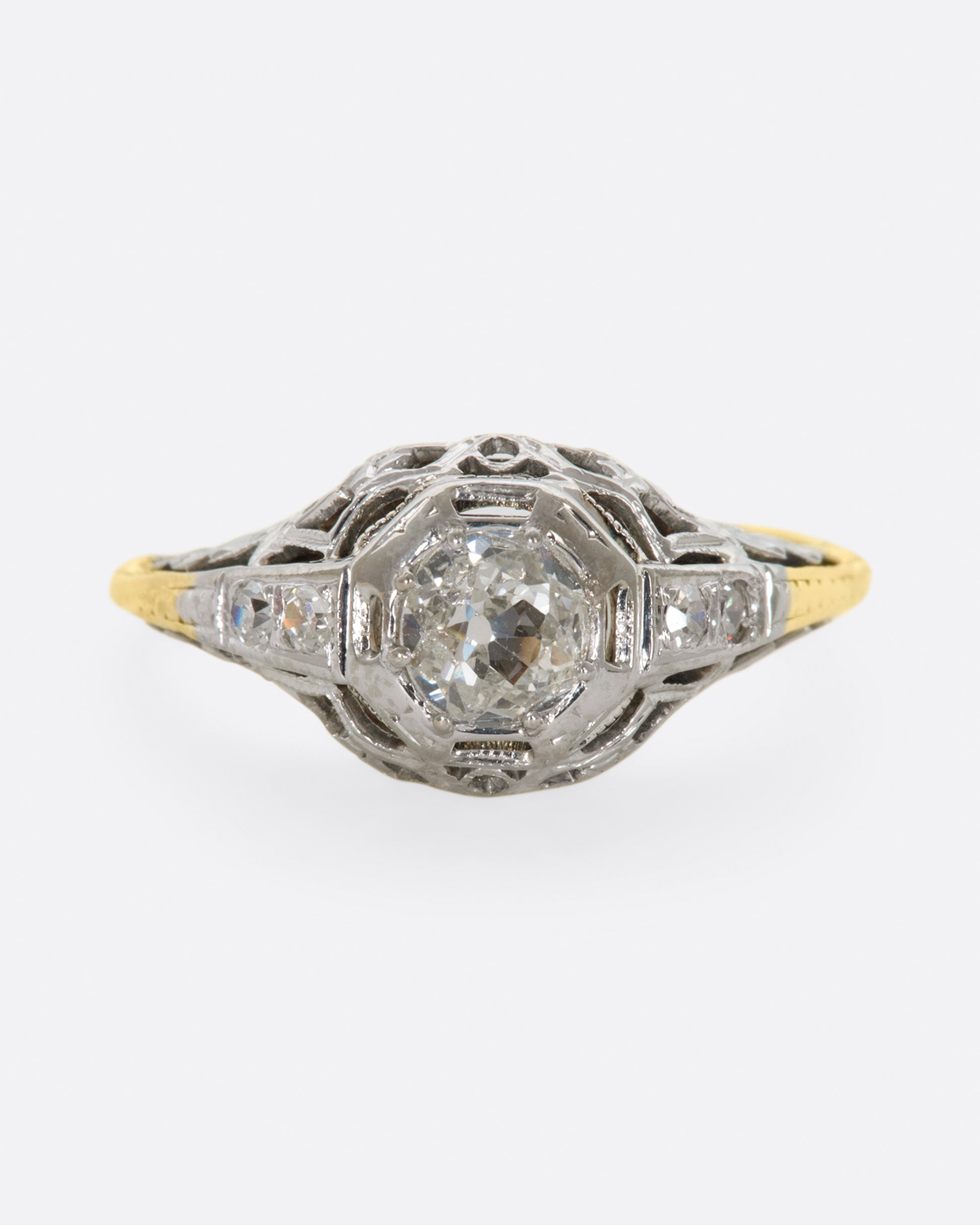 A white gold filigree ring with old mine cut center diamond and a yellow gold band. View from the front.