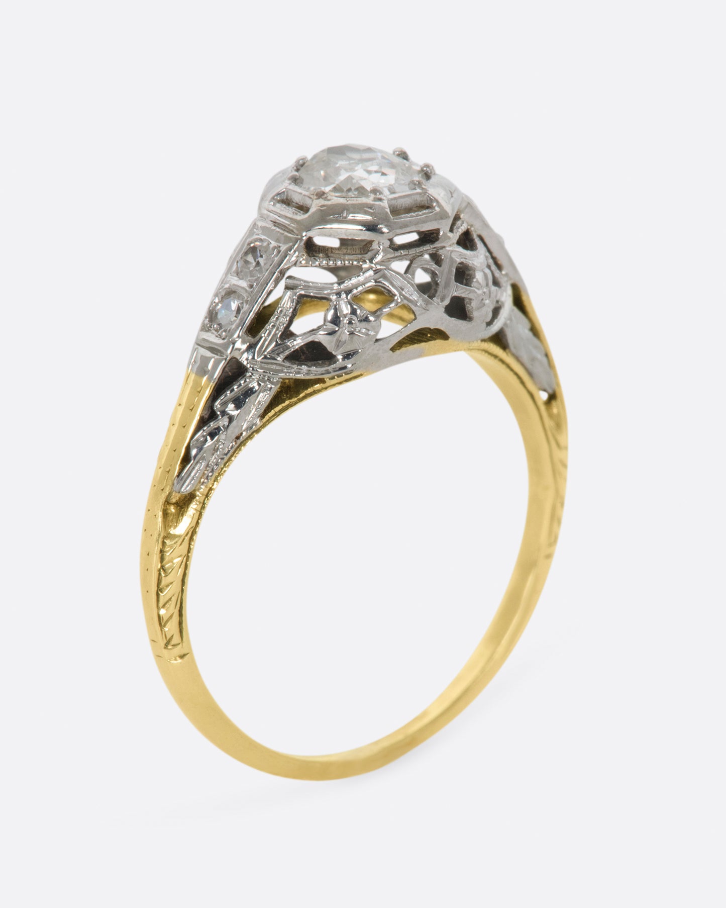 A white gold filigree ring with old mine cut center diamond and a yellow gold band. View standing up.