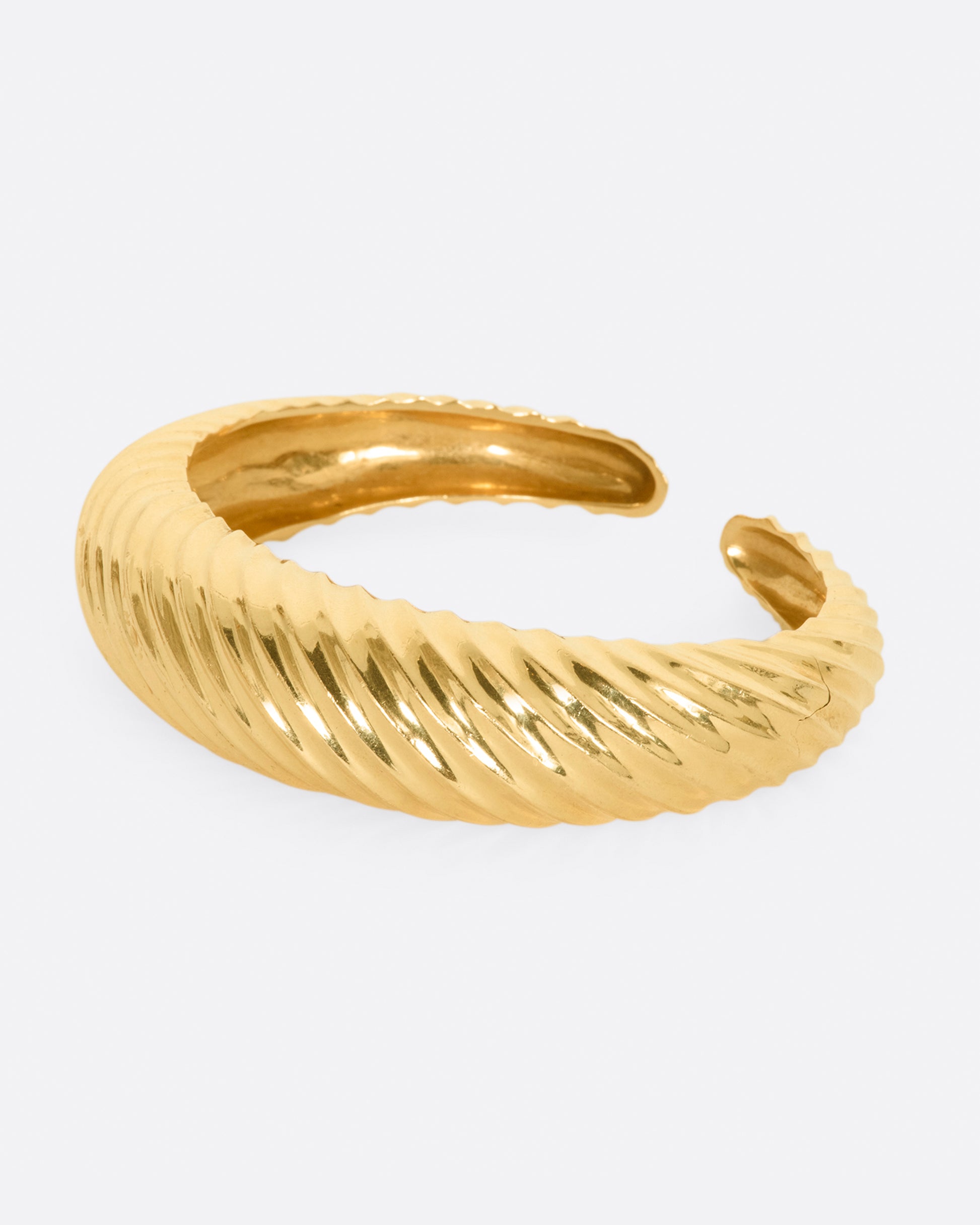 Yellow gold cuff with ridges that create a twisted look. View from the left side.