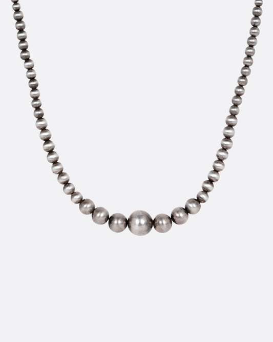 A silver beaded necklace, shown from the front.