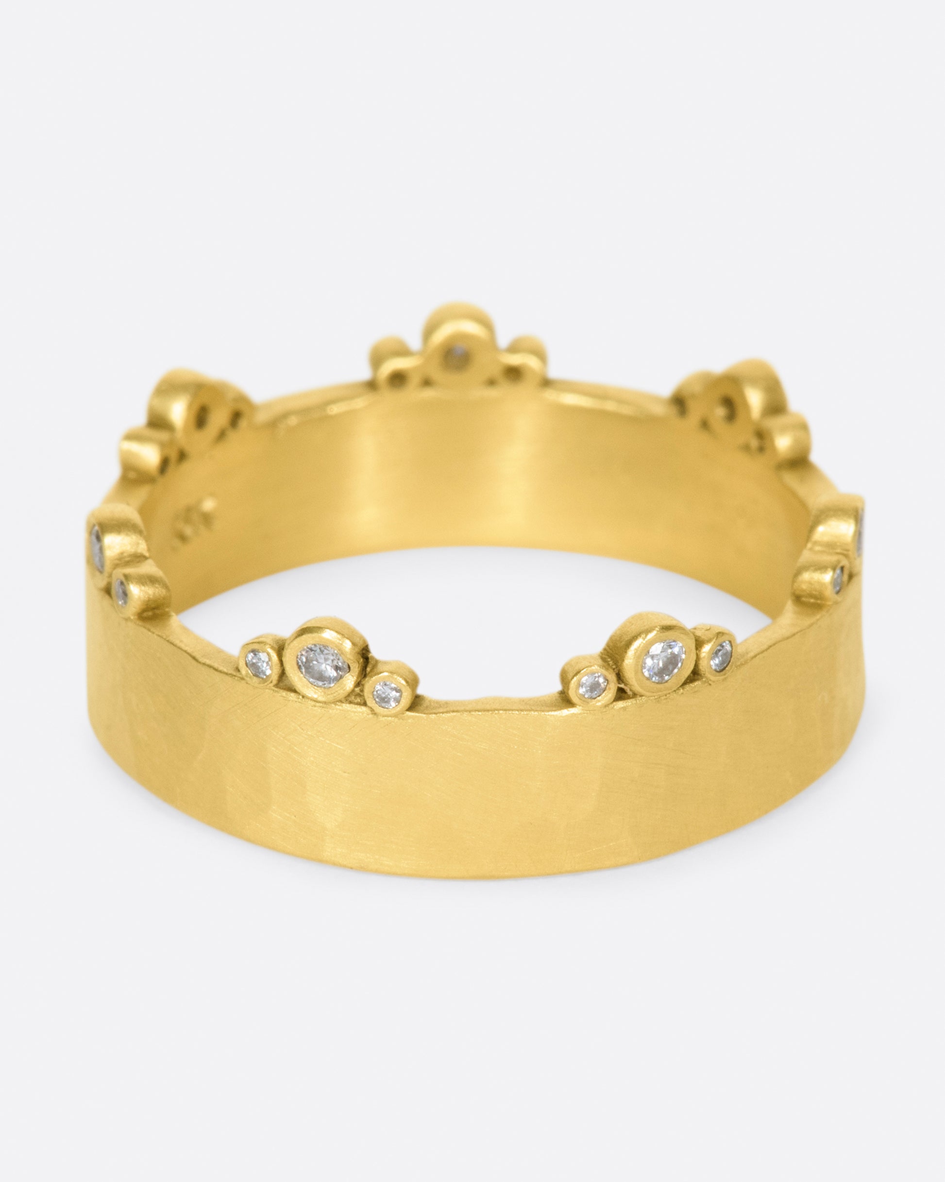 A wide, hammered, matte gold band with stations of diamonds along one edge.