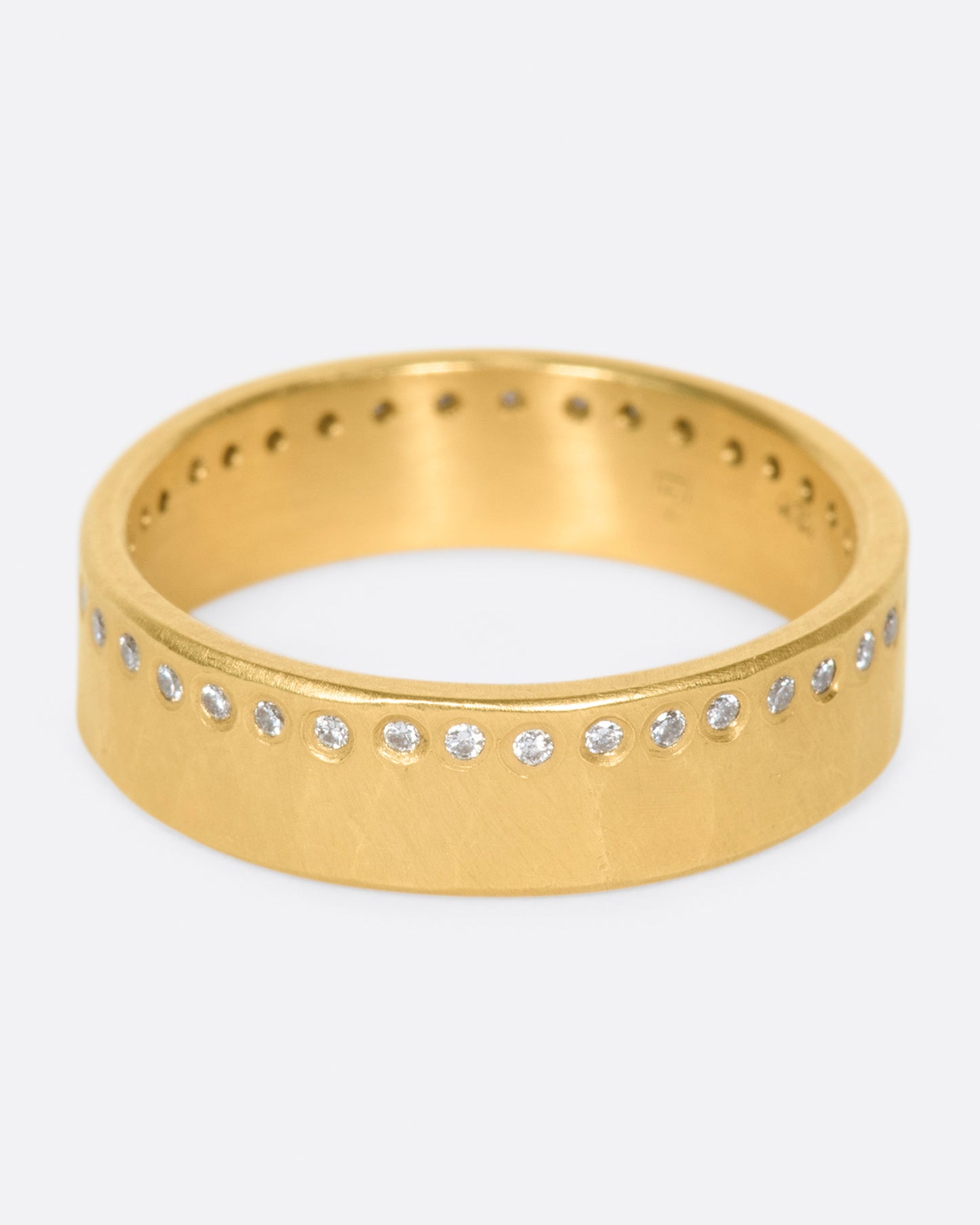 A hammered, matte gold band with a line of round diamonds all the way around.