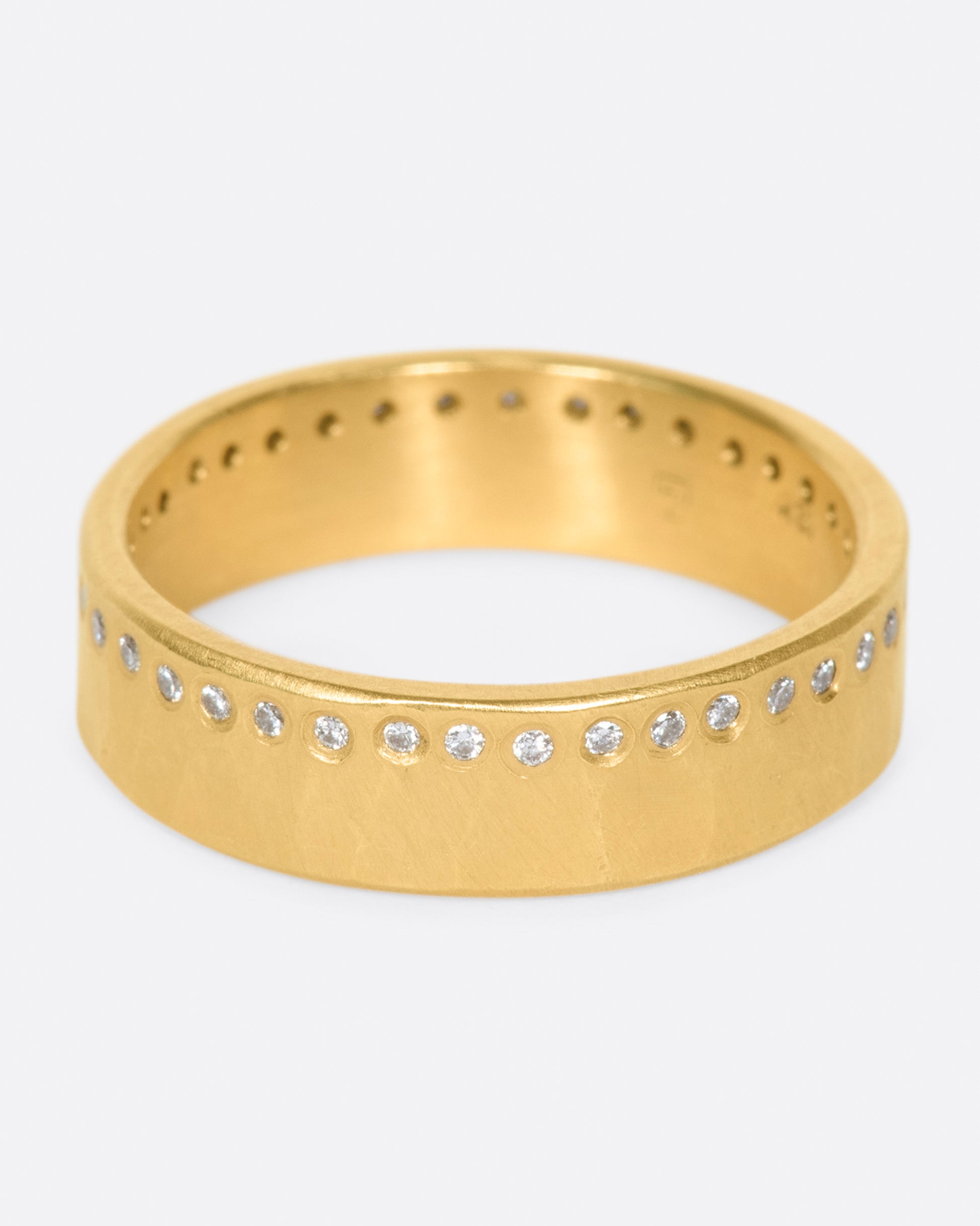 A hammered, matte gold band with a line of round diamonds all the way around.