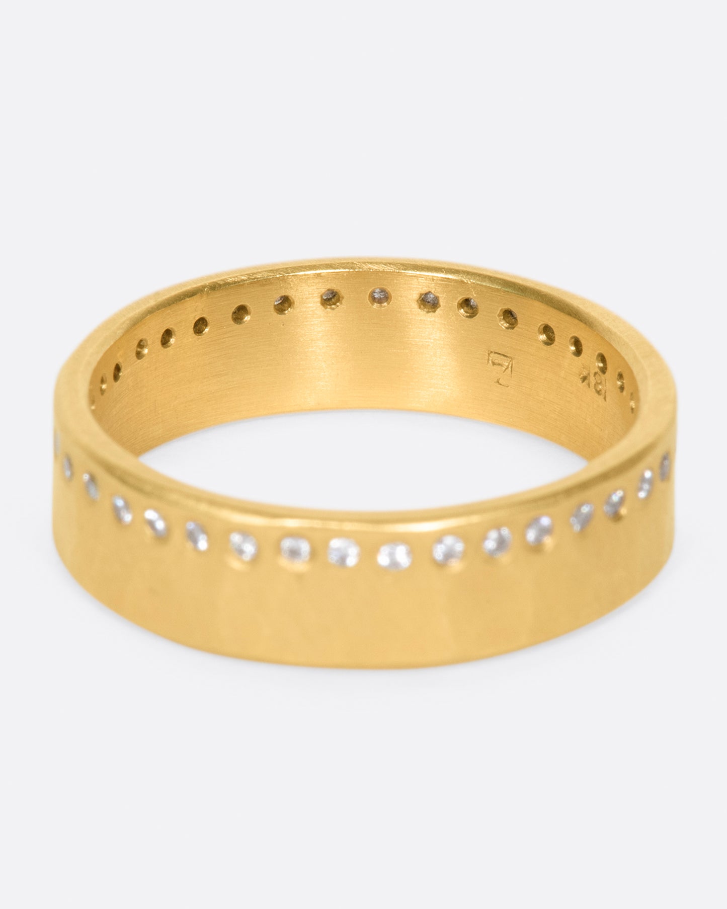 A hammered, matte gold band with a line of round diamonds all the way around.